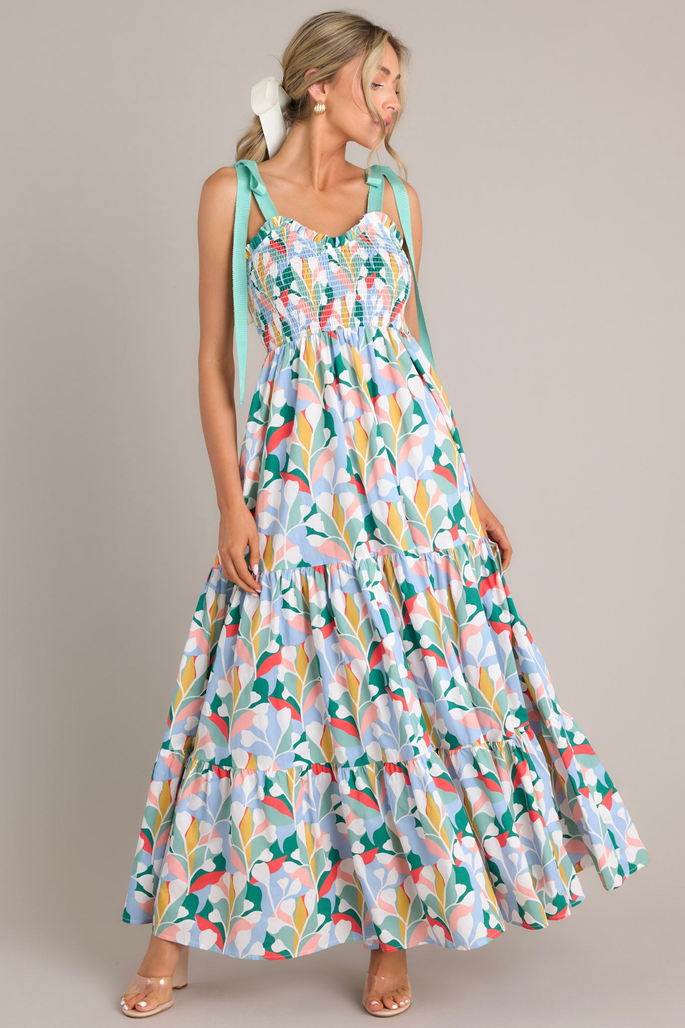 Full front view of this cotton dress that features a sweetheart neckline with ruffle detailing, adjustable self-tie shoulder straps, a smocked bodice, and a long, tiered skirt.