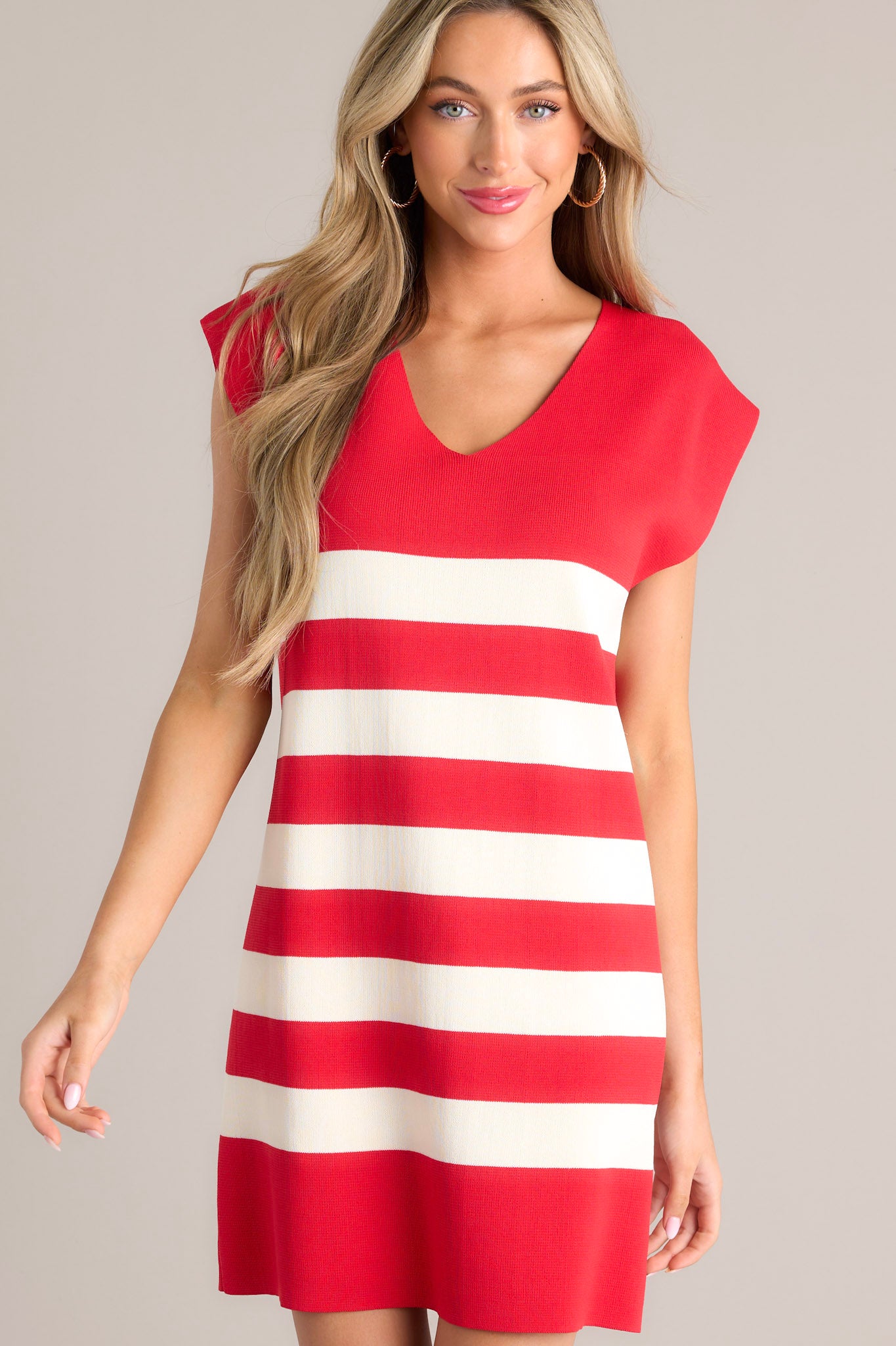 Front view of this red dress that red stripe mini dress that features a v-neckline, cap sleeves, a classic stripe pattern, a knit fabric, and a mini length.