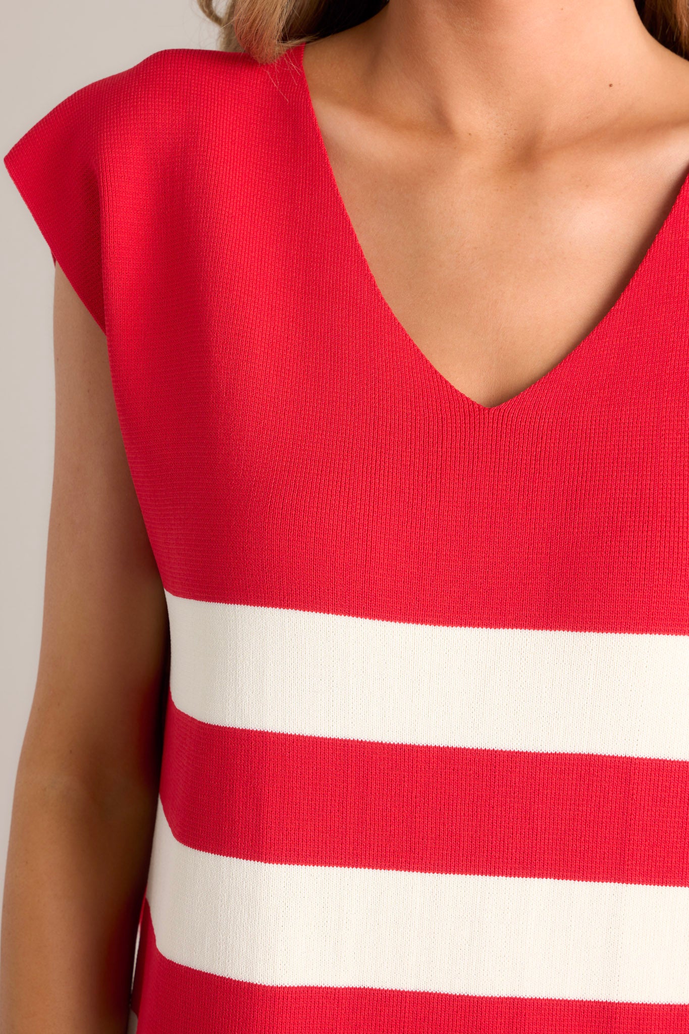 Close up view of this red stripe mini dress that features a v-neckline, cap sleeves, a classic stripe pattern, a knit fabric, and a mini length.