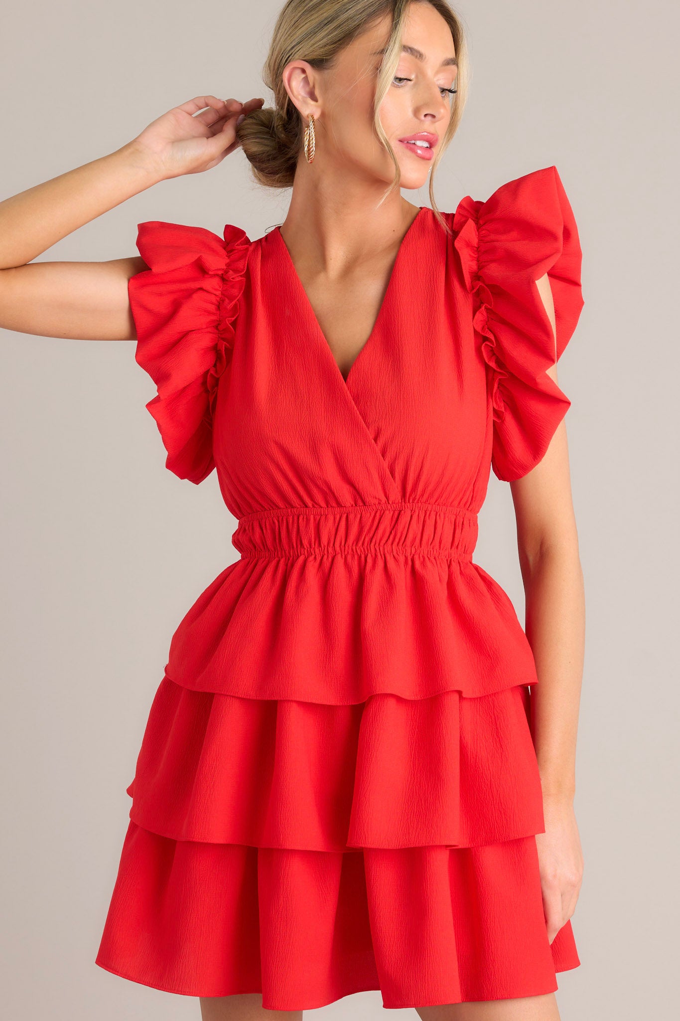 Red mini dress with a V-neckline, ruffled sleeves, and tiered skirt layers.