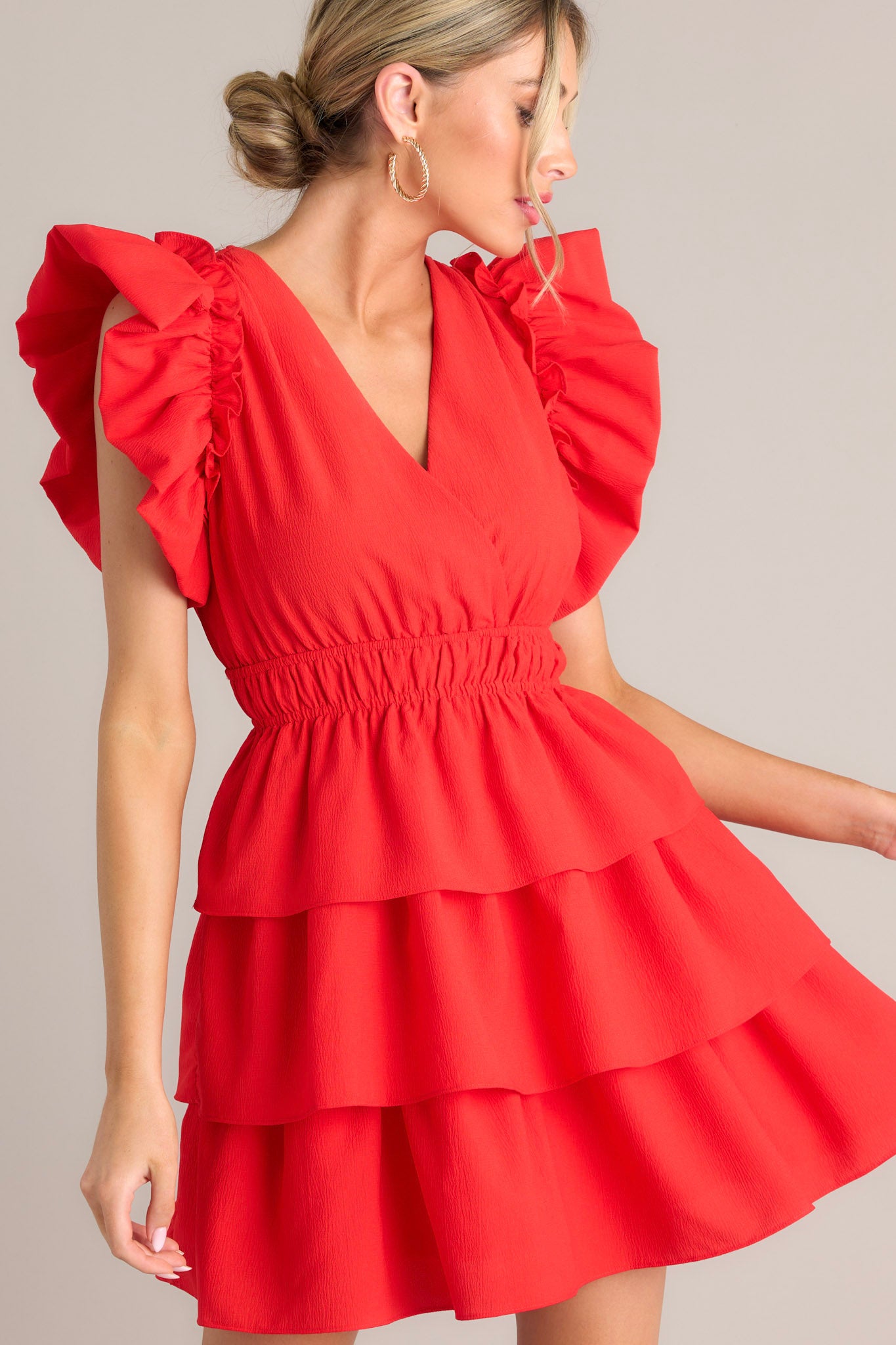 Short red dress with a wrap-style V-neck, ruffled sleeve details, and a layered skirt