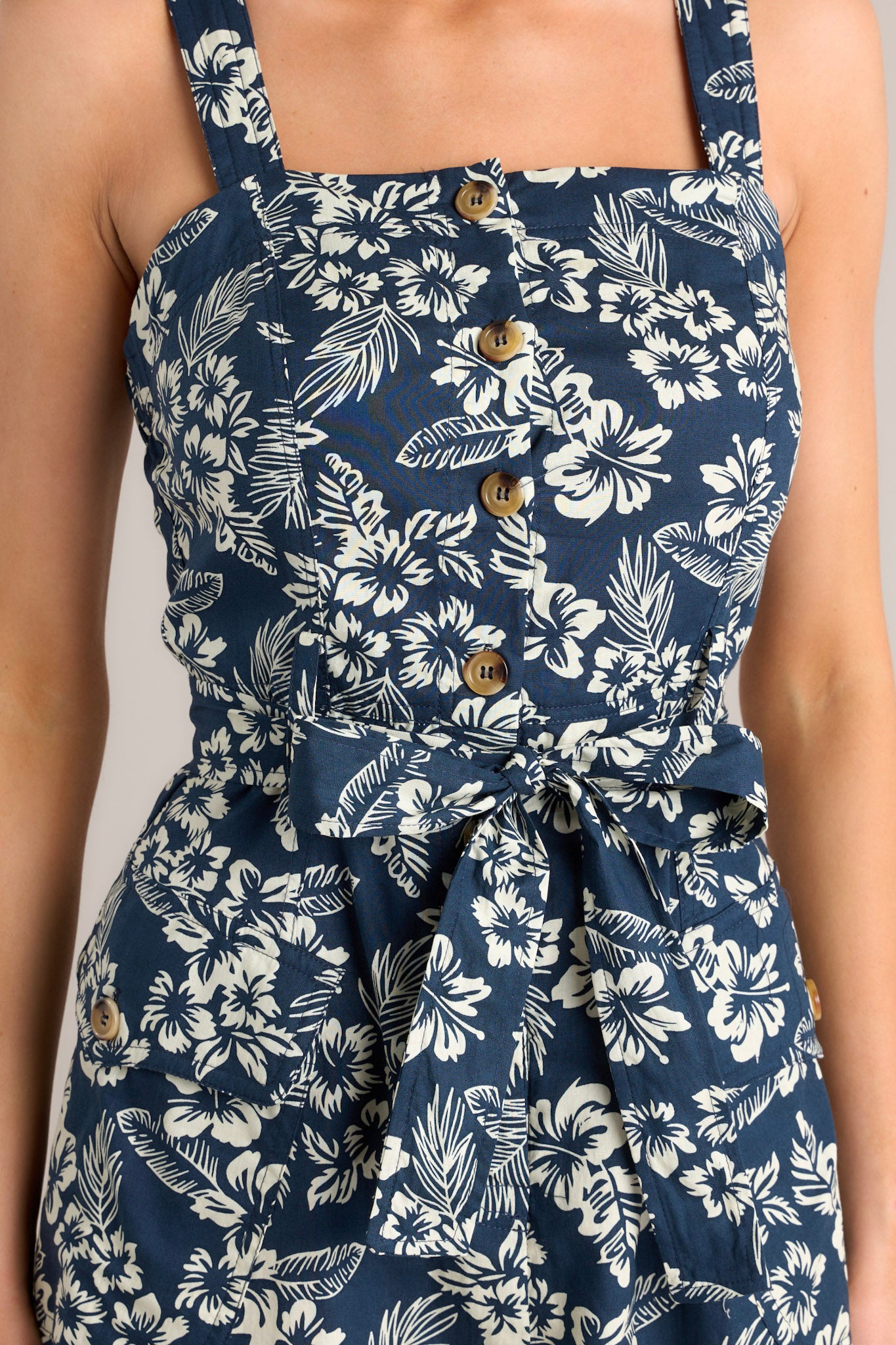 Close-up of the square neckline, thick straps, and functional button front bodice on a navy midi dress with a self-tie waist belt and buttoned hip pockets.