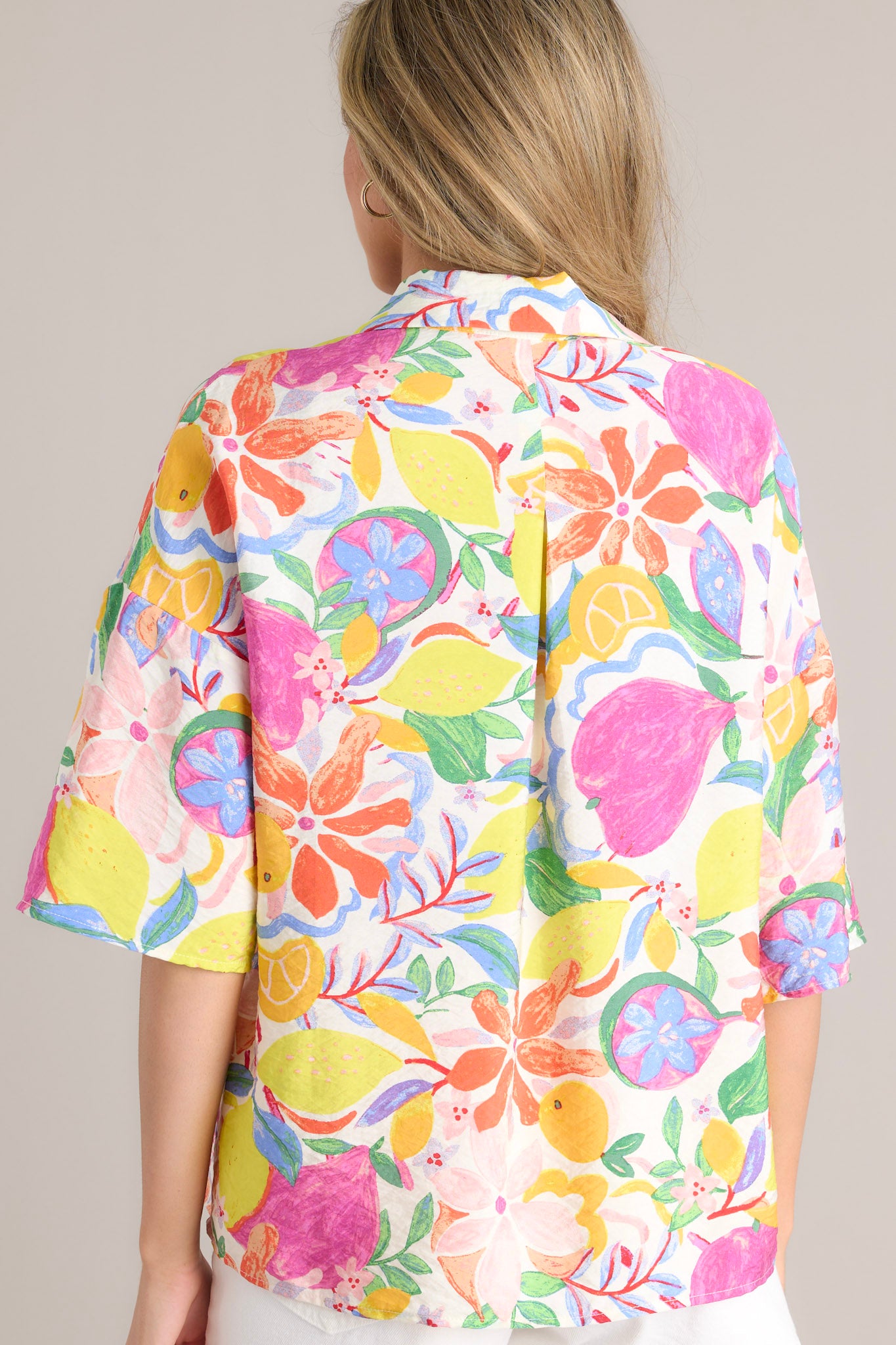 Back view of this top that features a collared neckline, a functional button front, and wide half sleeves.