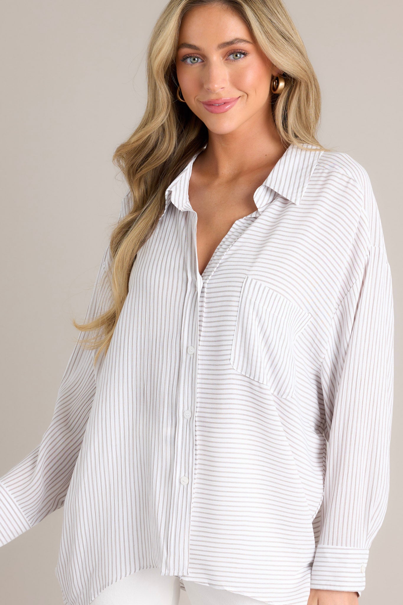 Front view of this white stripe top that features a collared neckline, a functional button front, a breast pocket, a unique stripe pattern going both vertically & horizontally, button cuffed long sleeves, and a split hemline.