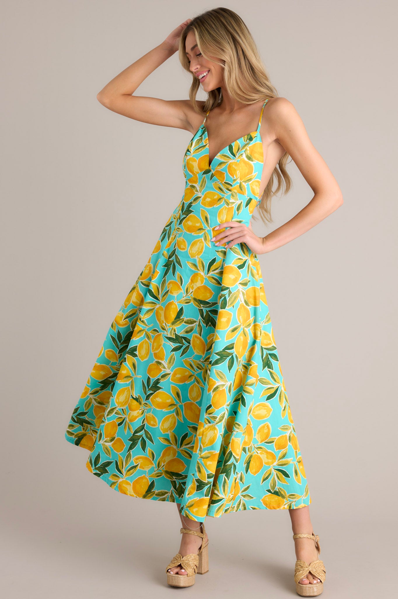 Aqua midi dress with v-neckline, adjustable thin straps, open back with buttons, hip pockets, and vibrant aqua lemon print.