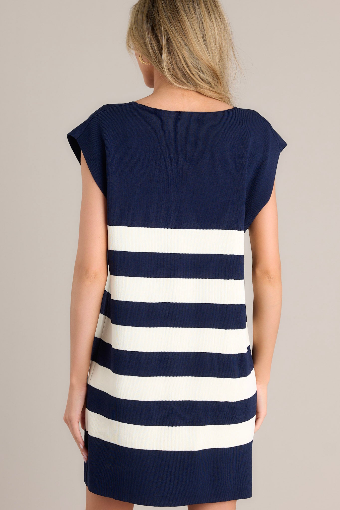 Back view of this navy stripe mini dress that features a v-neckline, cap sleeves, a classic stripe pattern, a knit fabric, and a mini length.