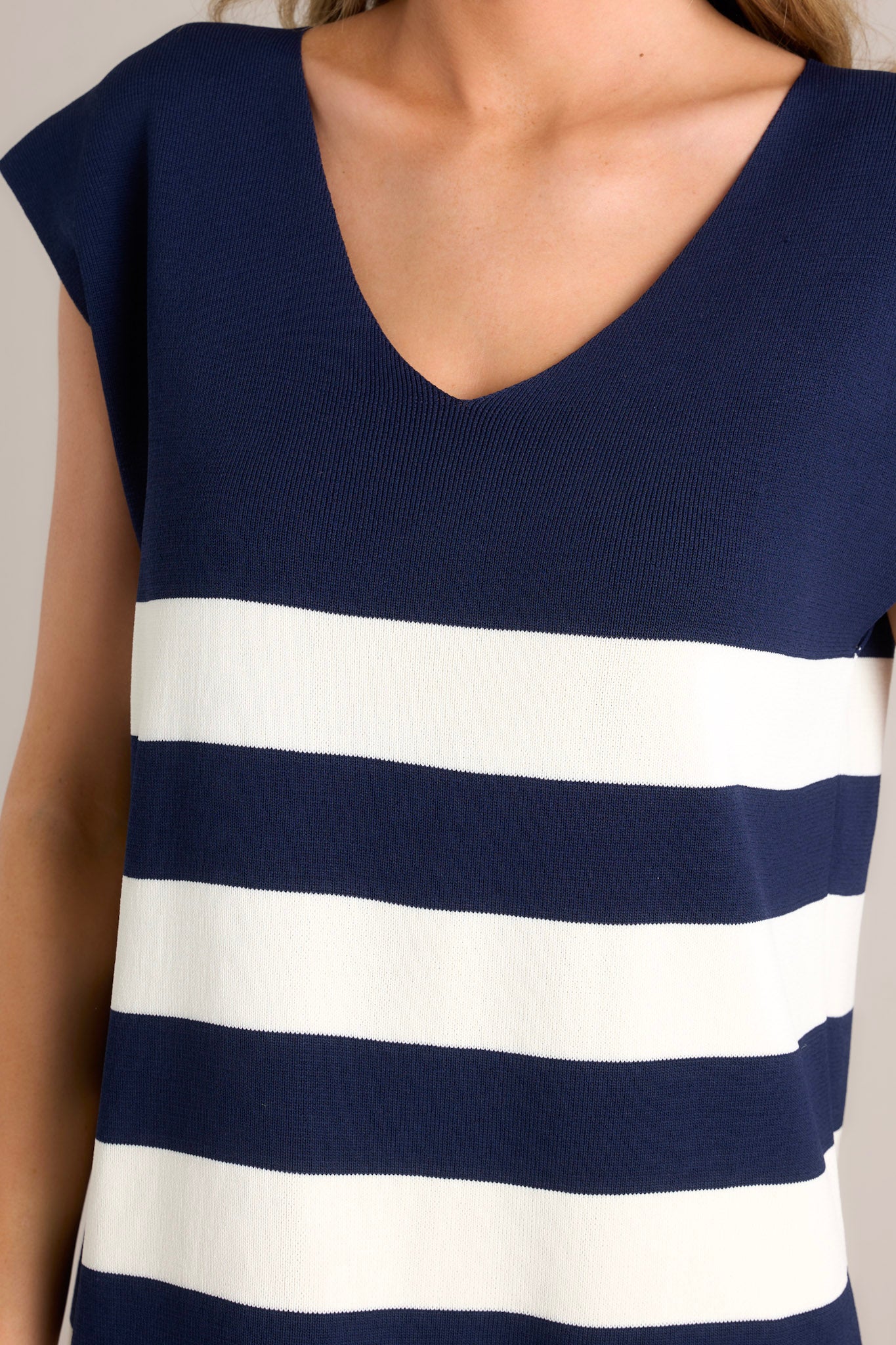 Close up view of this navy stripe mini dress features a v-neckline, cap sleeves, a classic stripe pattern, a knit fabric, and a mini length.