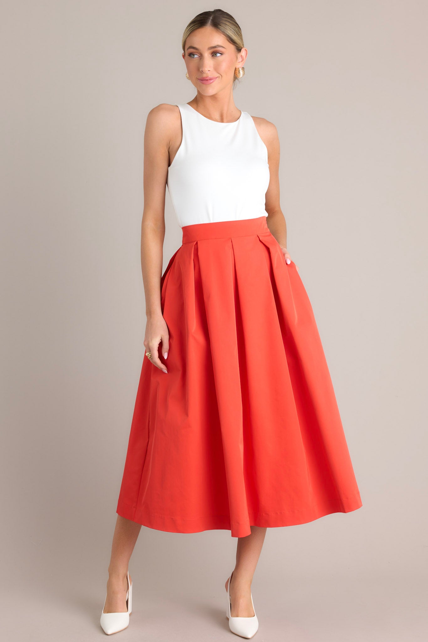 Full body view of this tomato red midi skirt that features a high waisted design, a discrete side zipper, a thick waistline and functional pockets.