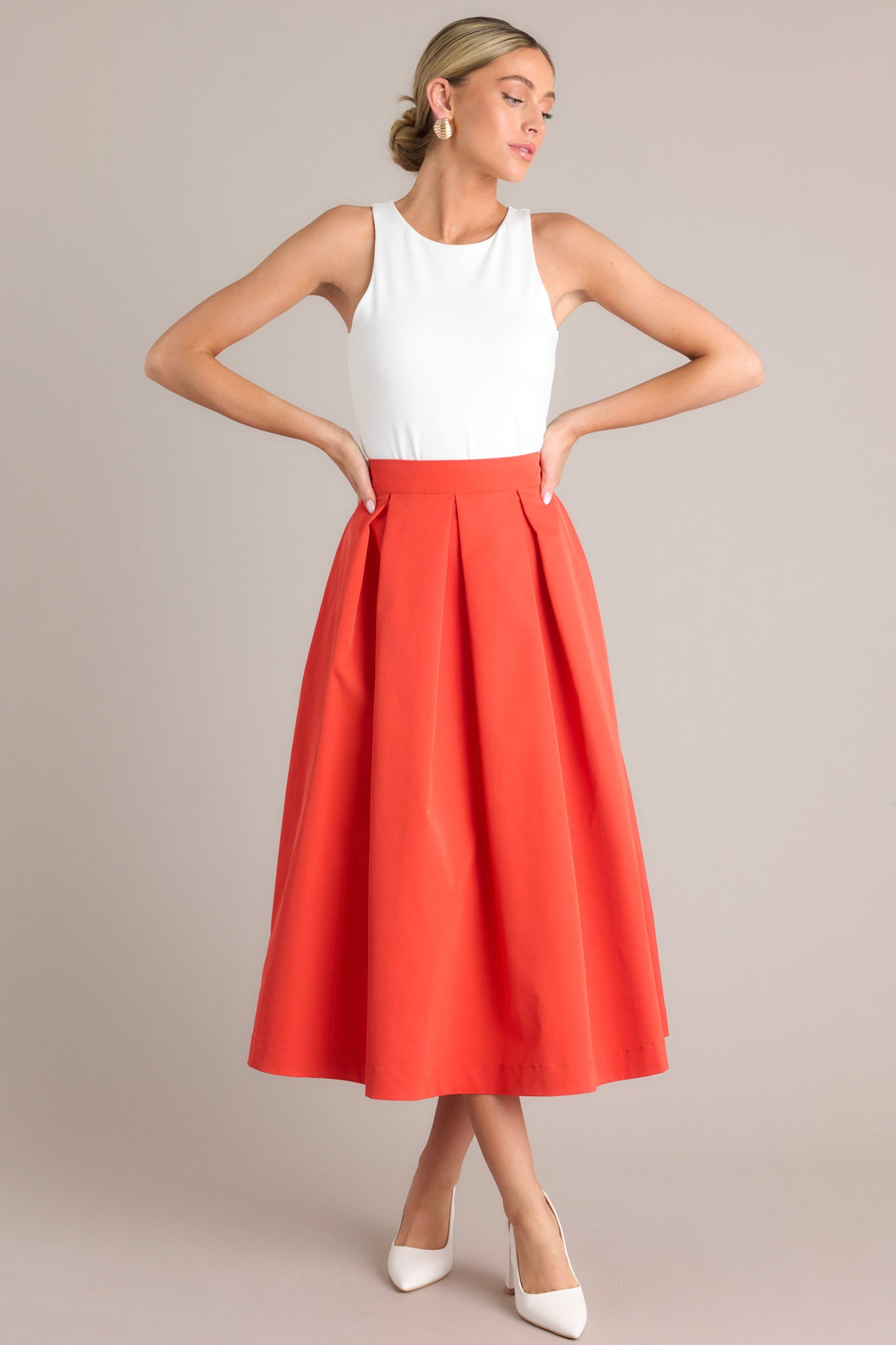 Front view of this tomato red midi skirt that features a high waisted design, a discrete side zipper, a thick waistline and functional pockets.
