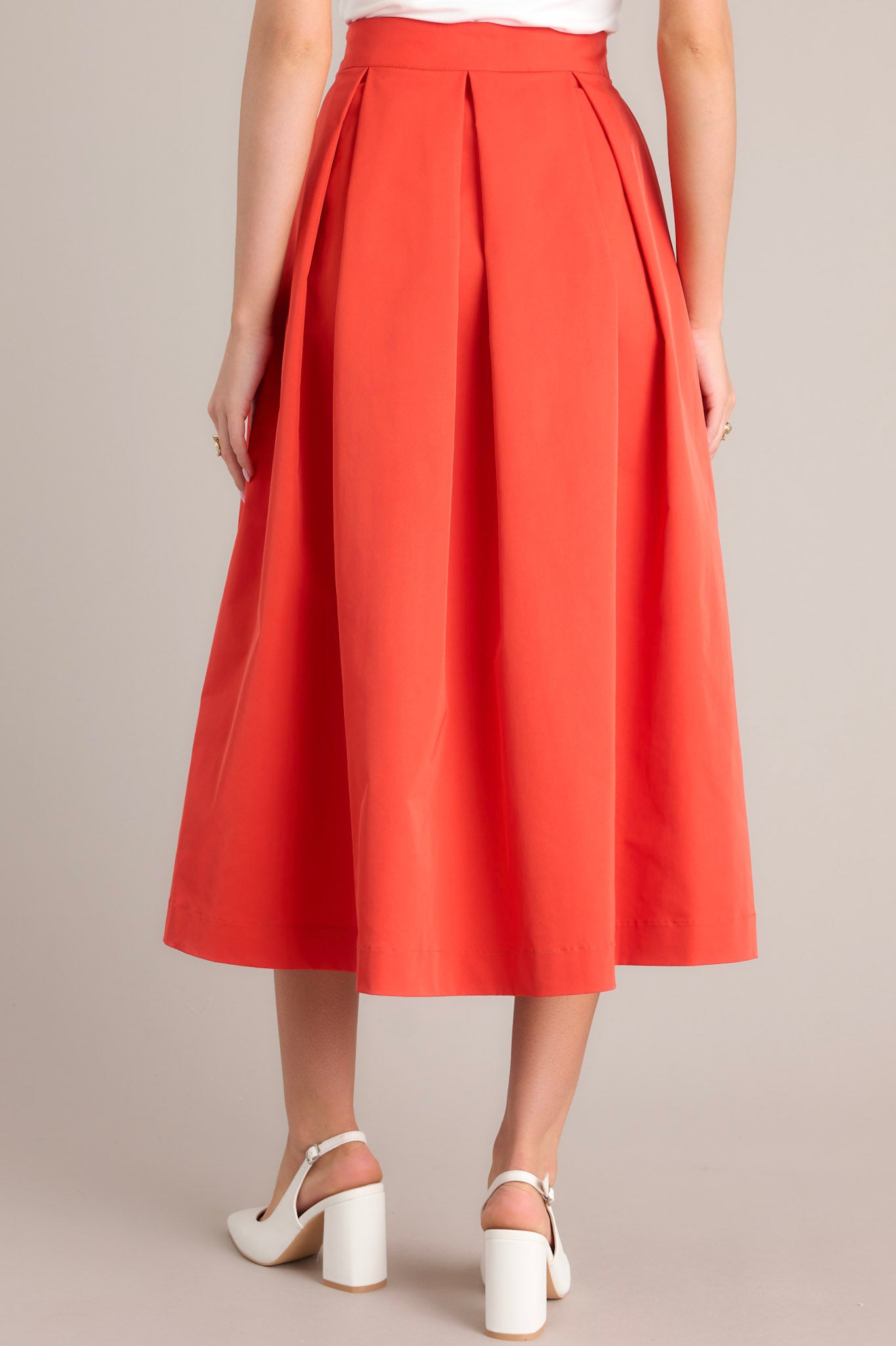 Back view of this tomato red midi skirt that features a high waisted design, a discrete side zipper, a thick waistline and functional pockets.