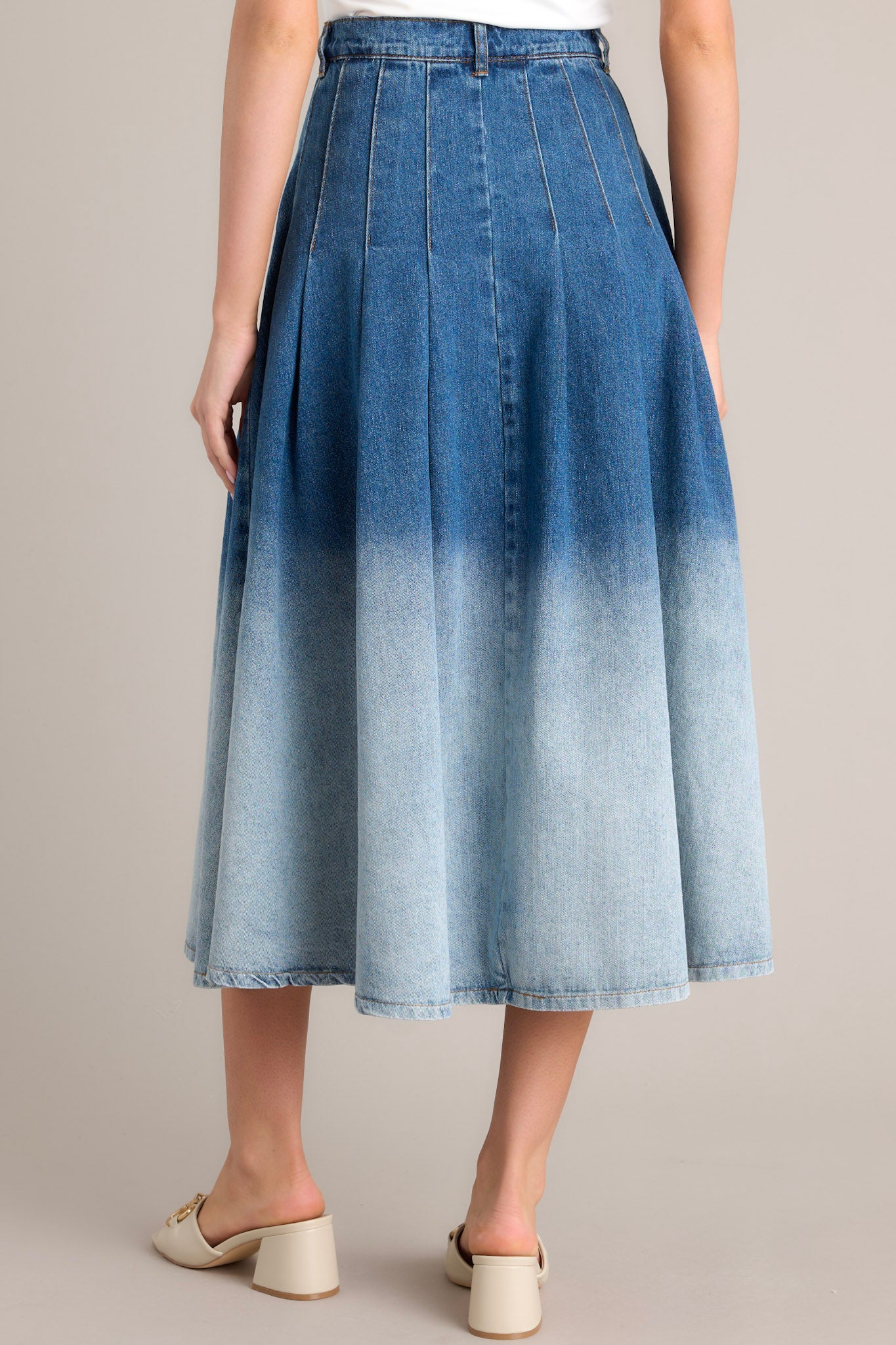 Back view of this skirt that features a high waisted design, a classic button & zipper closure, belt loops, functional front pockets, subtle pleats, and an ombré gradient.