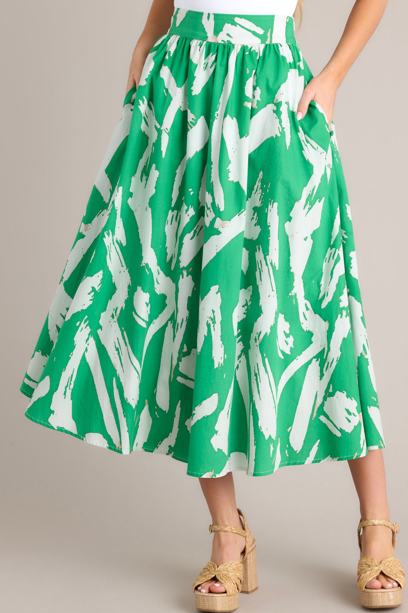 Front view of this green skirt that features a side zipper closure, functional waist pockets, and a gorgeous kelly green abstract print.