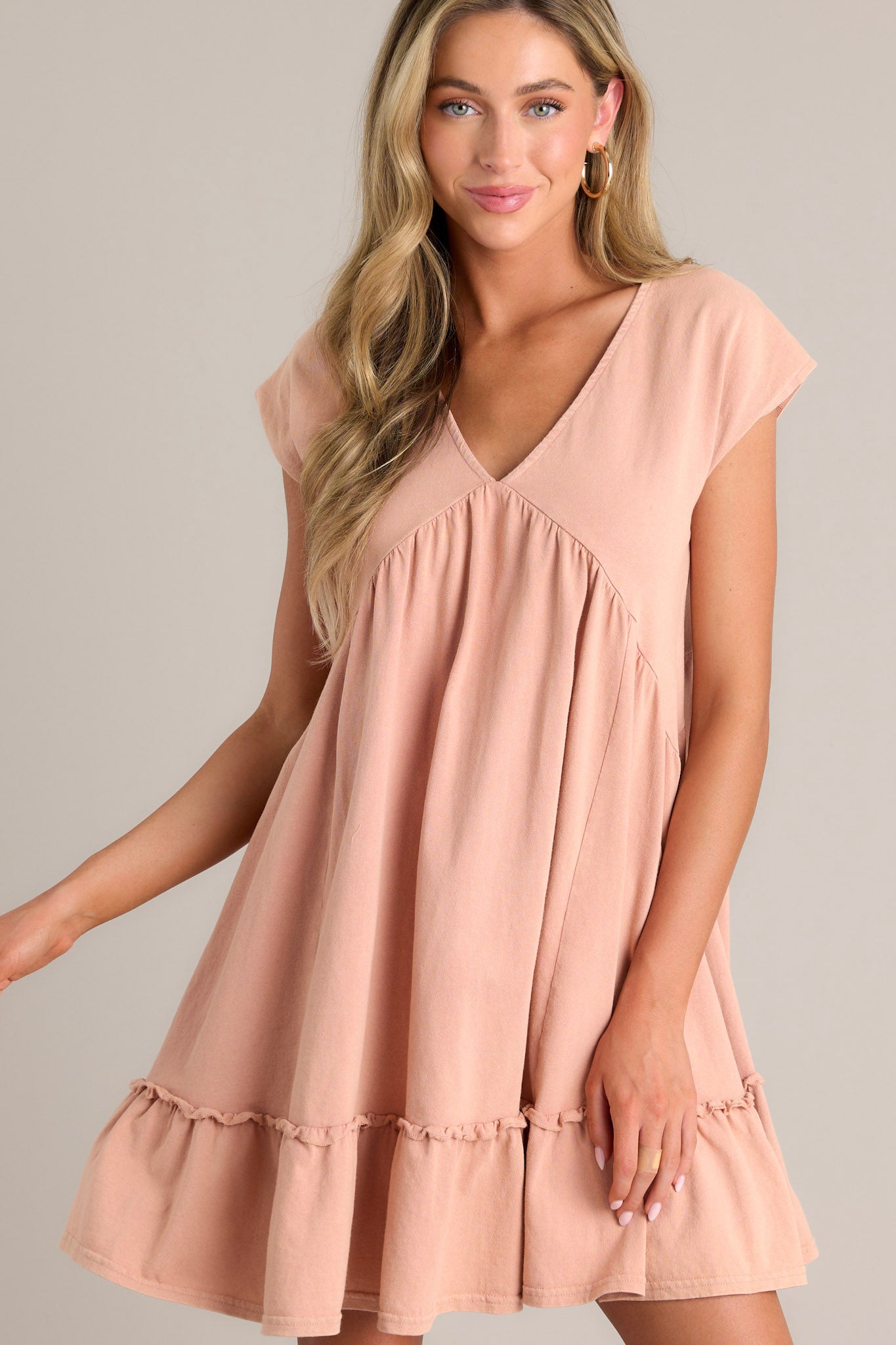 This peach mini dress features a v-neckline, ruching below the bust line, and short cap sleeves.