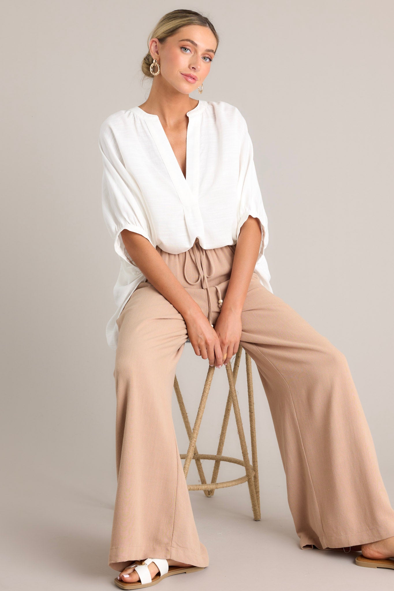 These tan pants feature a high waisted design, a thin elastic waistband, a self-tie drawstring, functional hip pockets, and a wide leg.