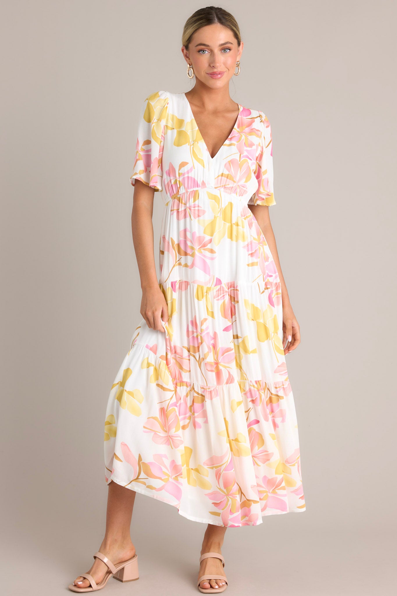 Front view of this floral maxi dress that features a v-neckline, an elastic waistband, a tiered design, and short flutter sleeves.