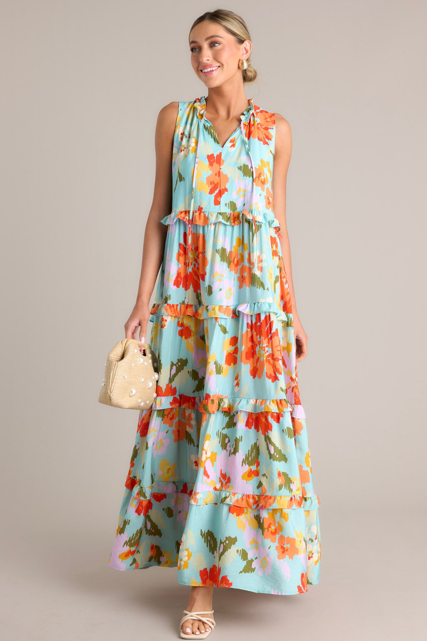 This floral maxi dress features a ruffled v-neckline with a self-tie feature, functional hip pockets, an abstract floral print, and a tiered design.