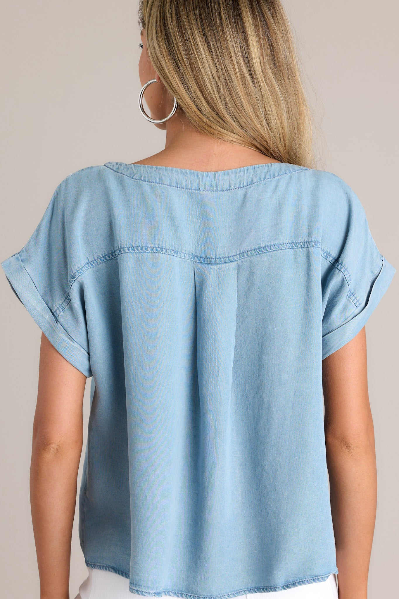 Back view of this light chambray top that features a crew neckline, a relaxed fit, and a wide cuffed short sleeves.