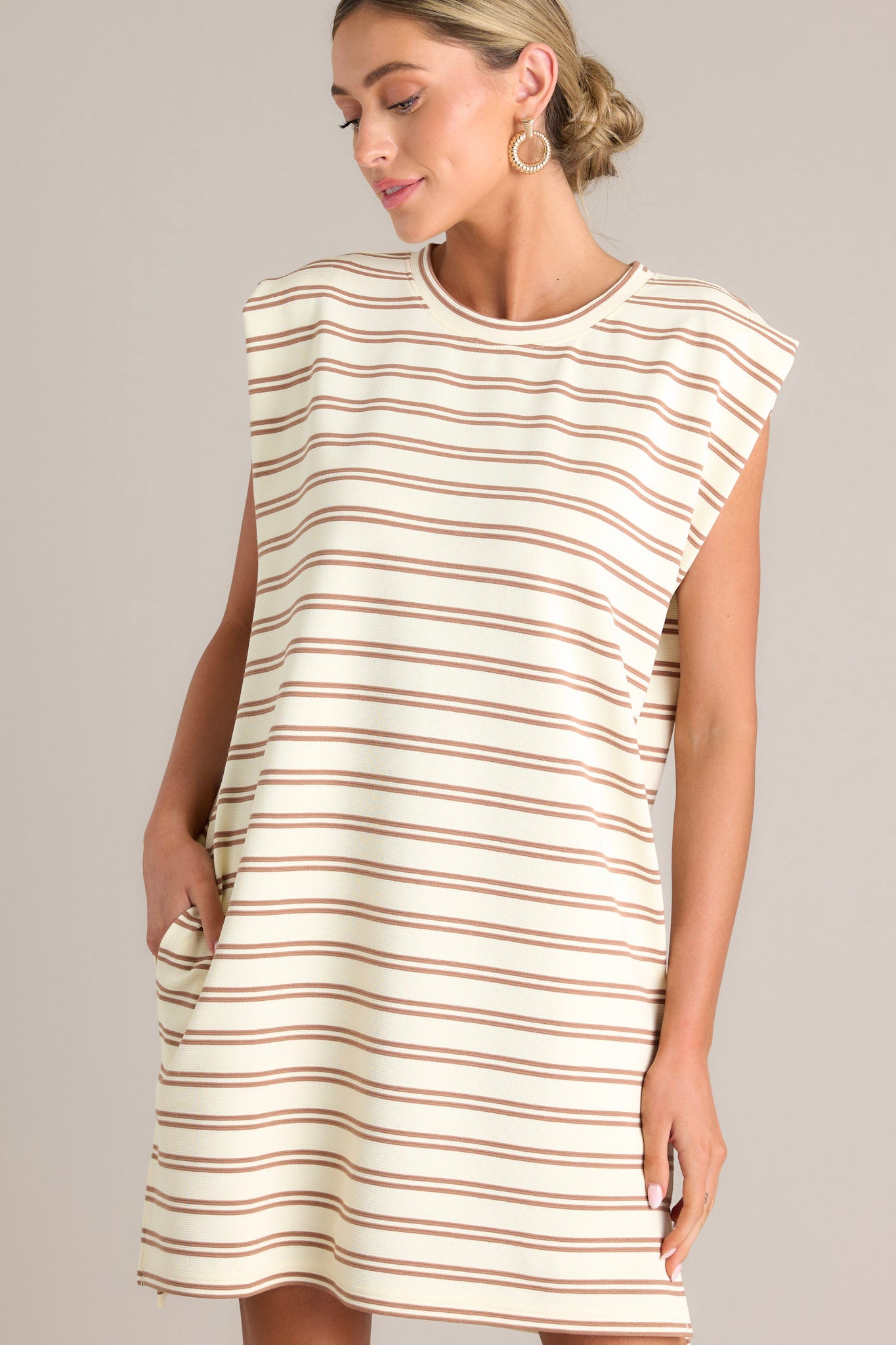 Angled front view of this stripe mini dress that features a crew neckline, short cap sleeves, a double stripe pattern, functional hip pockets, and a split hemline.