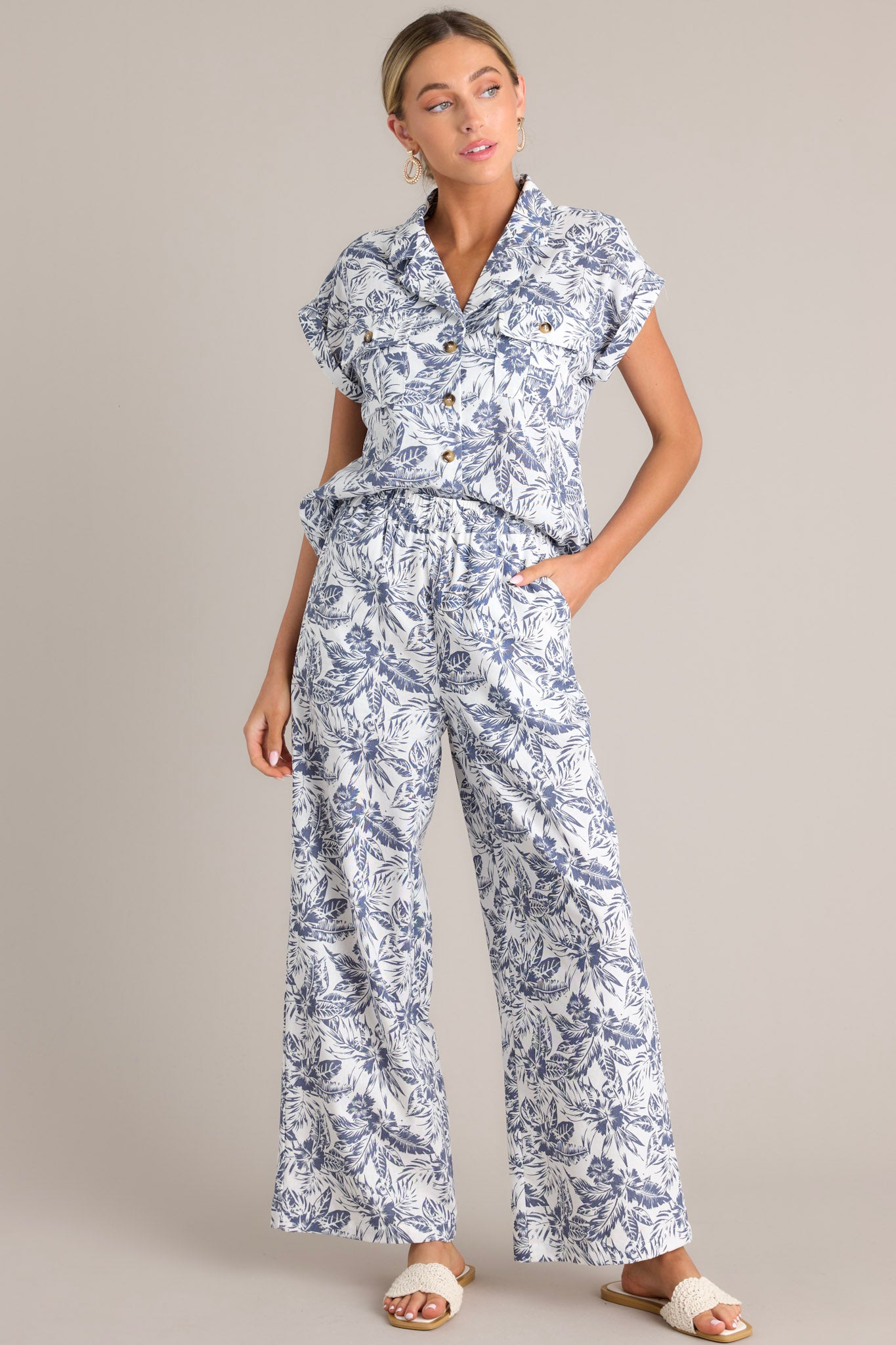 These blue and white pants feature a high waisted design, an elastic waistband, functional hip pockets, a unique pattern, and a wide leg design.