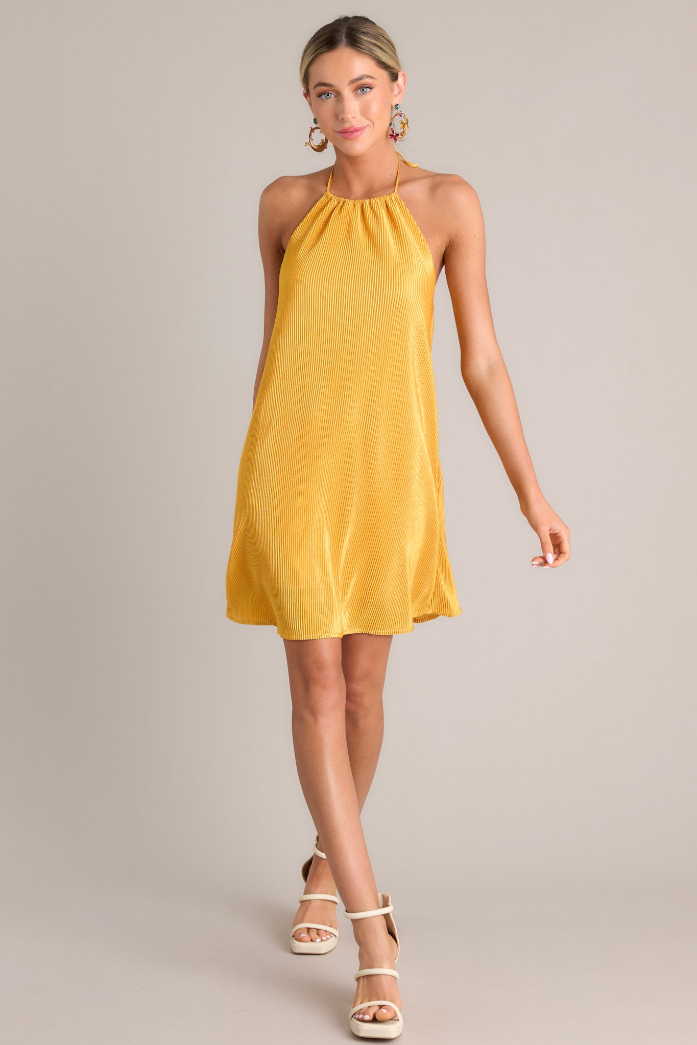 Full body view of this goldenrod mini dress that features a self-tie halter neckline, an elastic band in the back, and an all over ribbed texture.