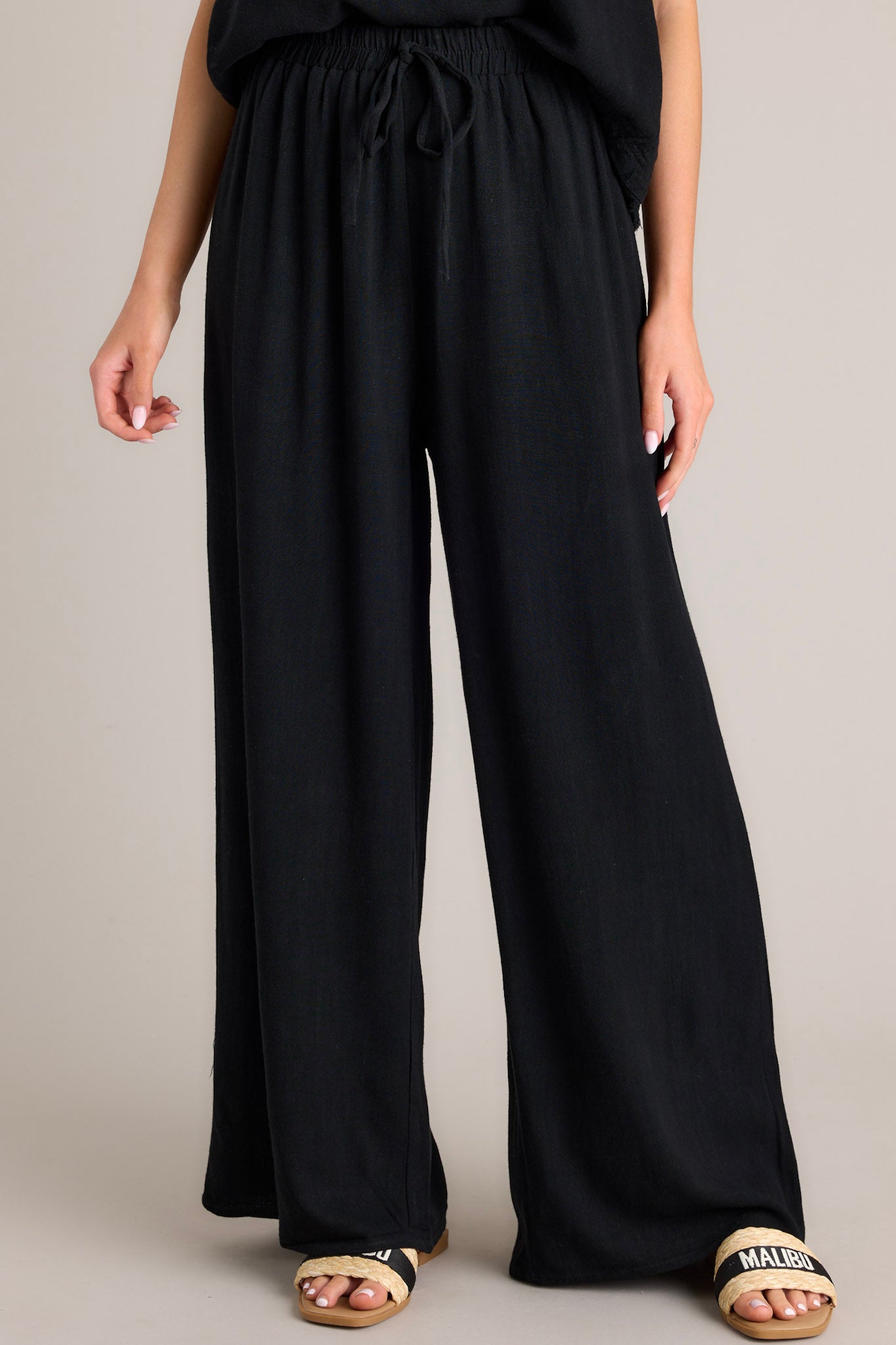 These black pants feature a high waisted design, an elastic waistband, a self-tie waist feature, and a wide leg.