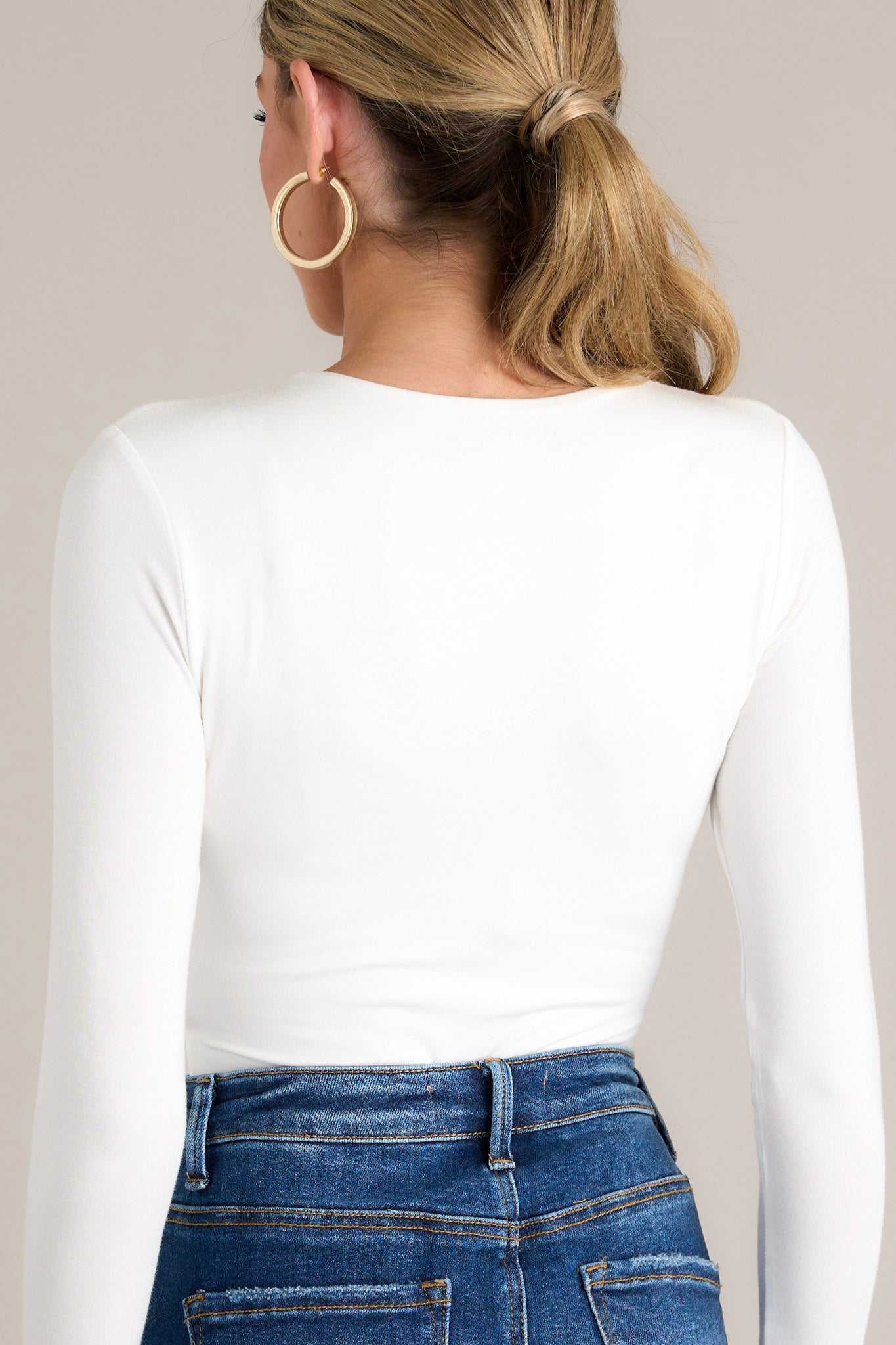 Back view of this bodysuit that features a crisscross V-neckline, long sleeves, and bottom snap button closures.