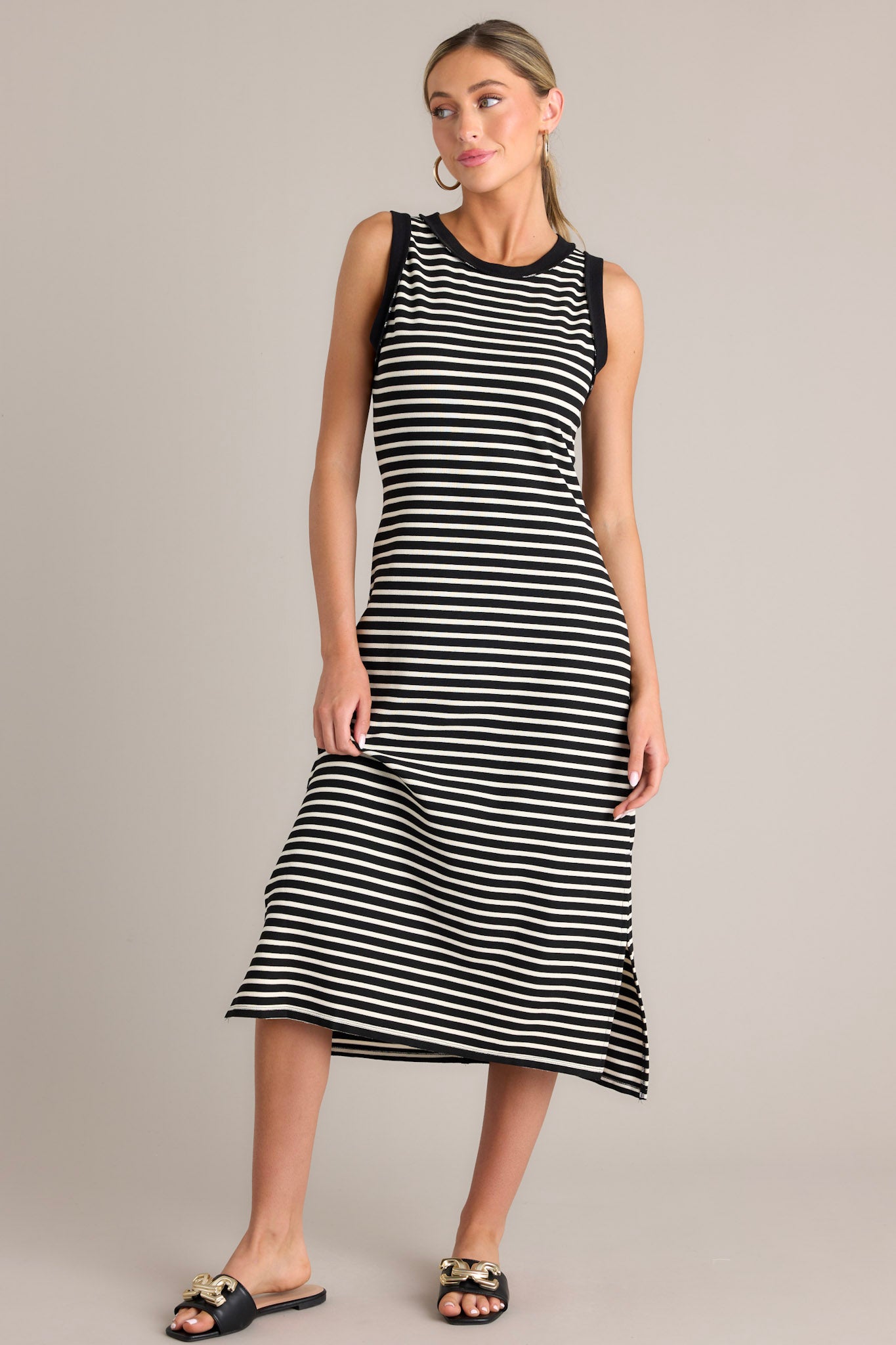 Full body view of this black stripe midi dress that features a crew neckline, a classic horizontal stripe design, and a split hemline.