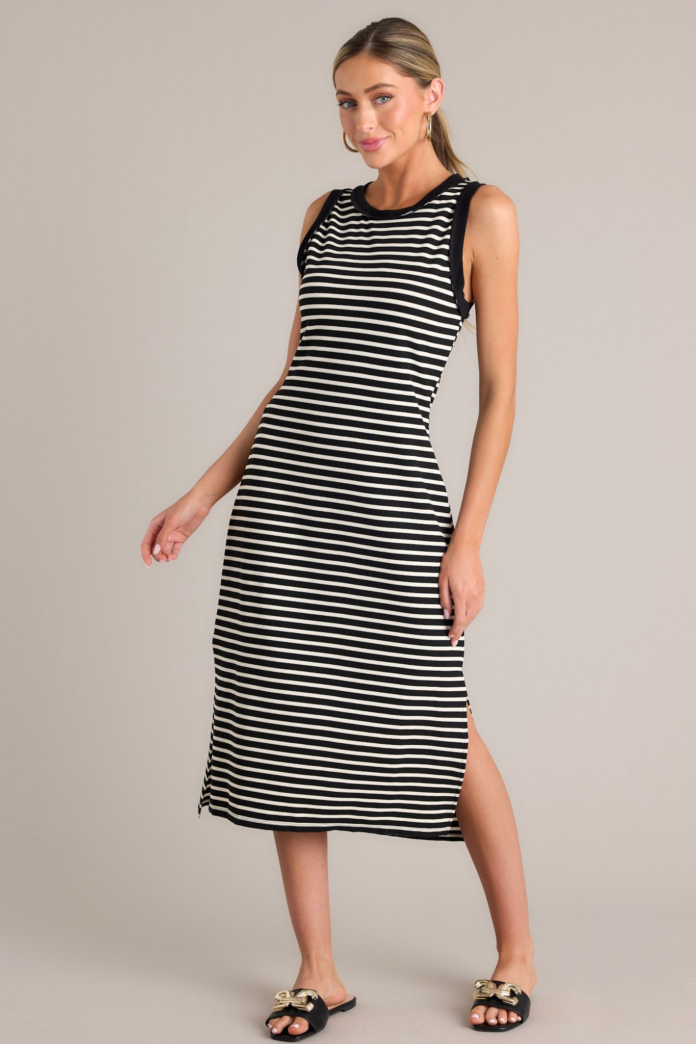 Side view of this black stripe midi dress that features a crew neckline, a classic horizontal stripe design, and a split hemline.