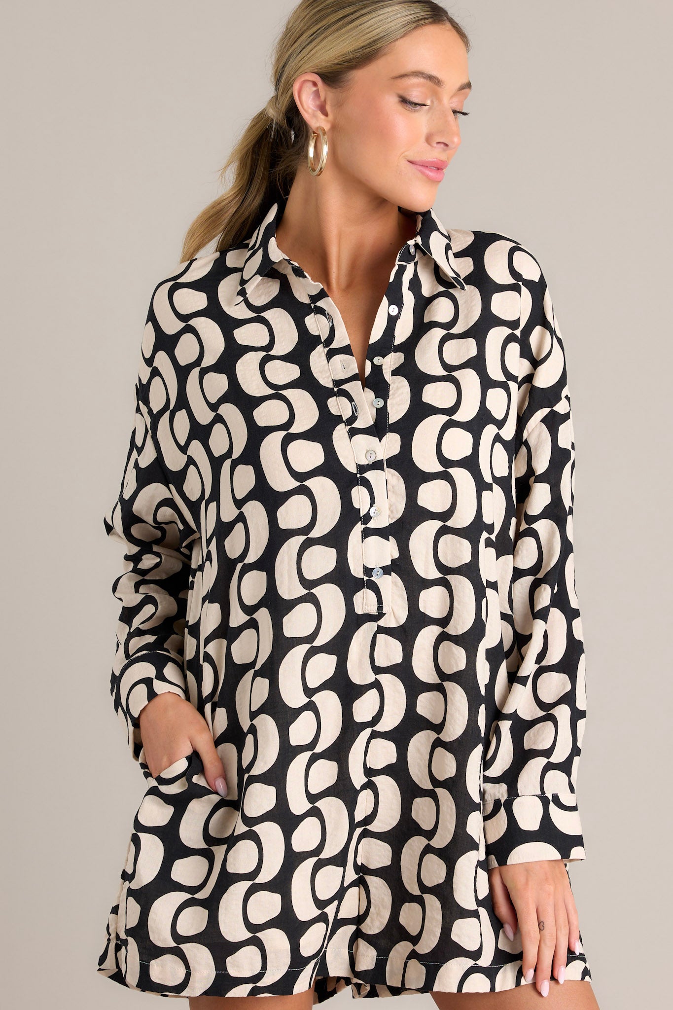 Front view of this abstract print romper features a collared neckline, functional buttons, functional hip pockets, and button cuffed long sleeves.