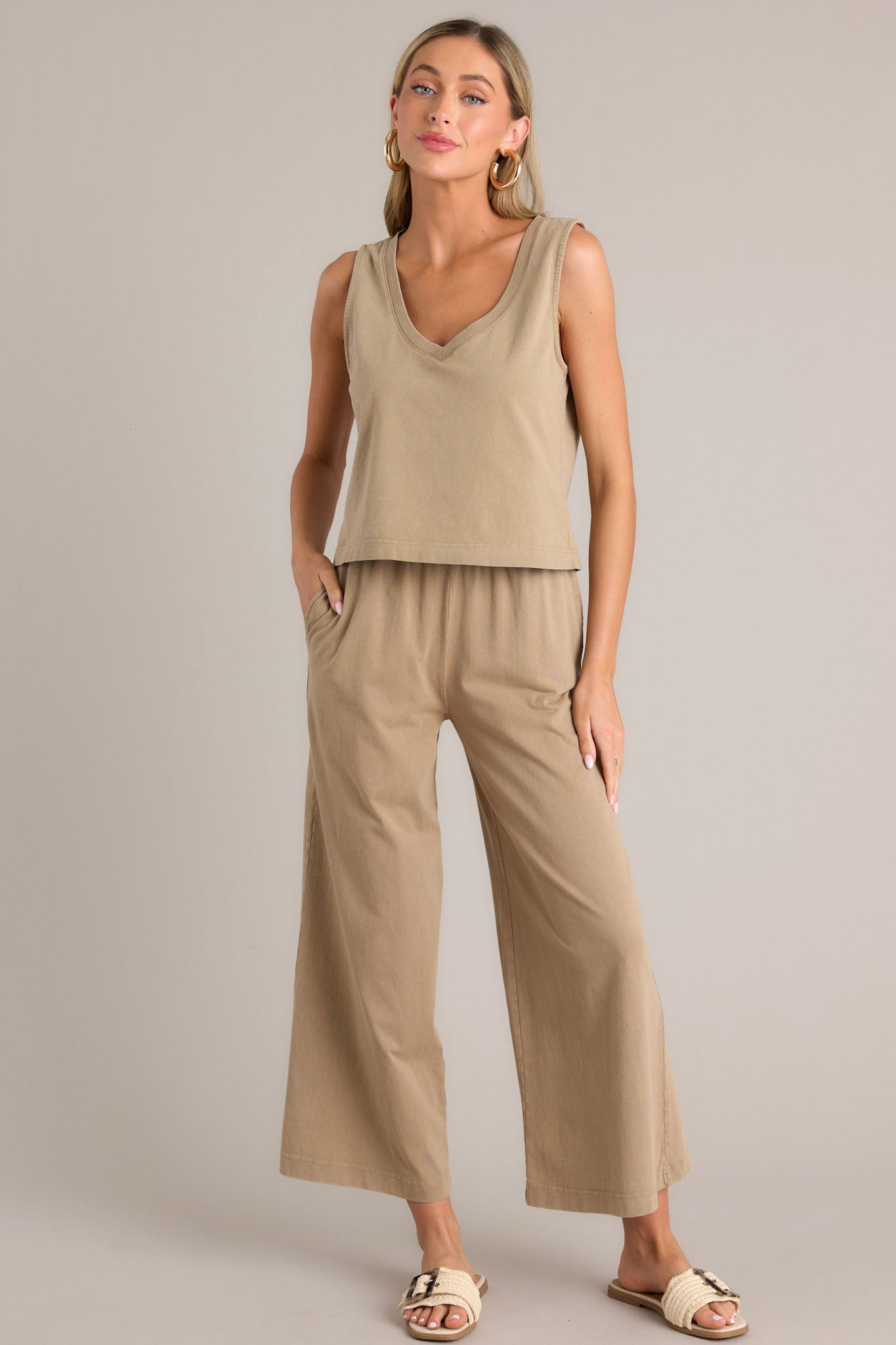 This light brown tank features a v-neckline, a sleeveless design, and a slightly cropped hemline.