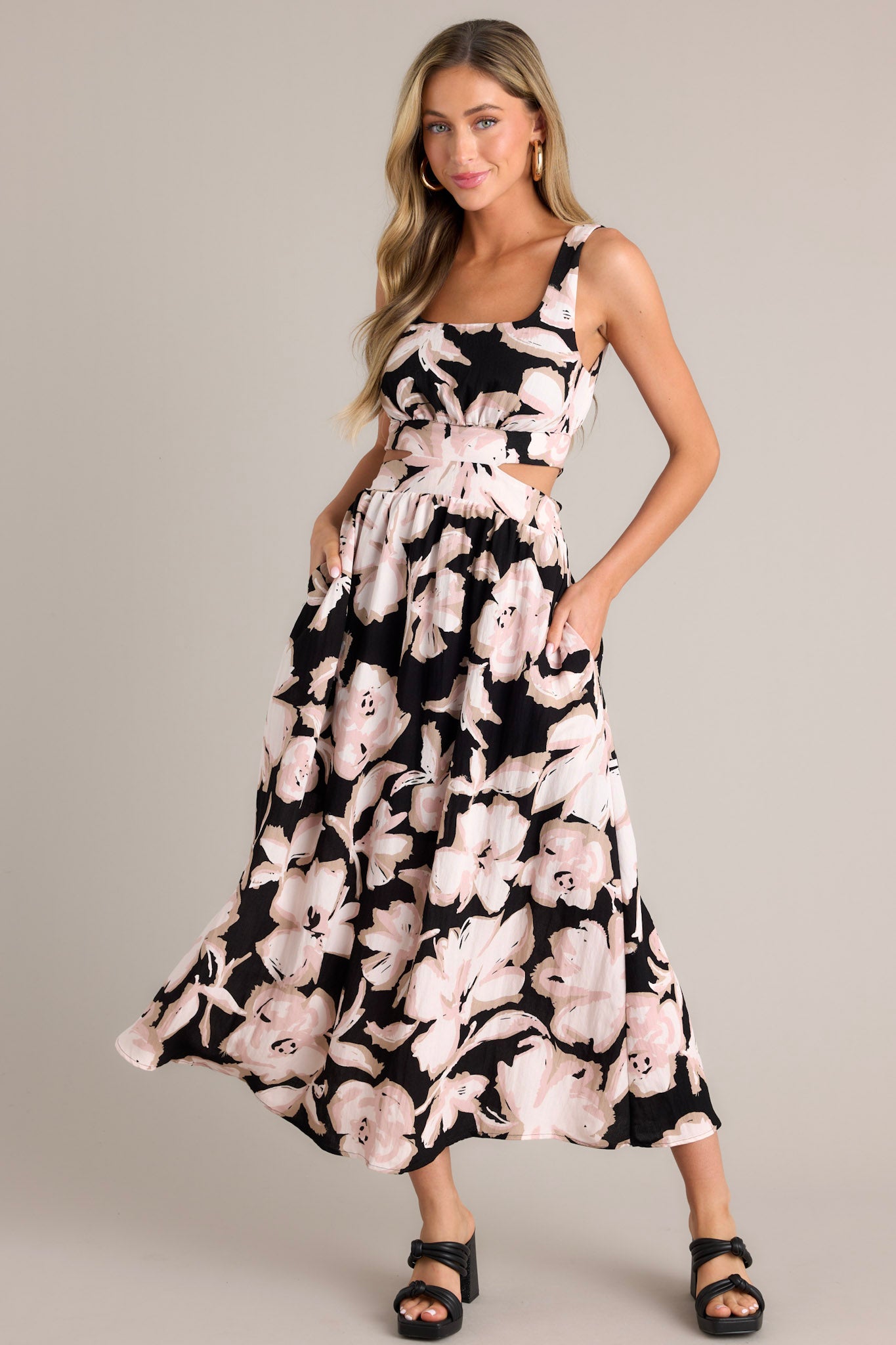 This black maxi dress features a square neckline, thick straps, an elastic back insert, a self-tie back feature, waist cutouts with a smocked back insert, functional hip pockets, and an all over floral pattern.
