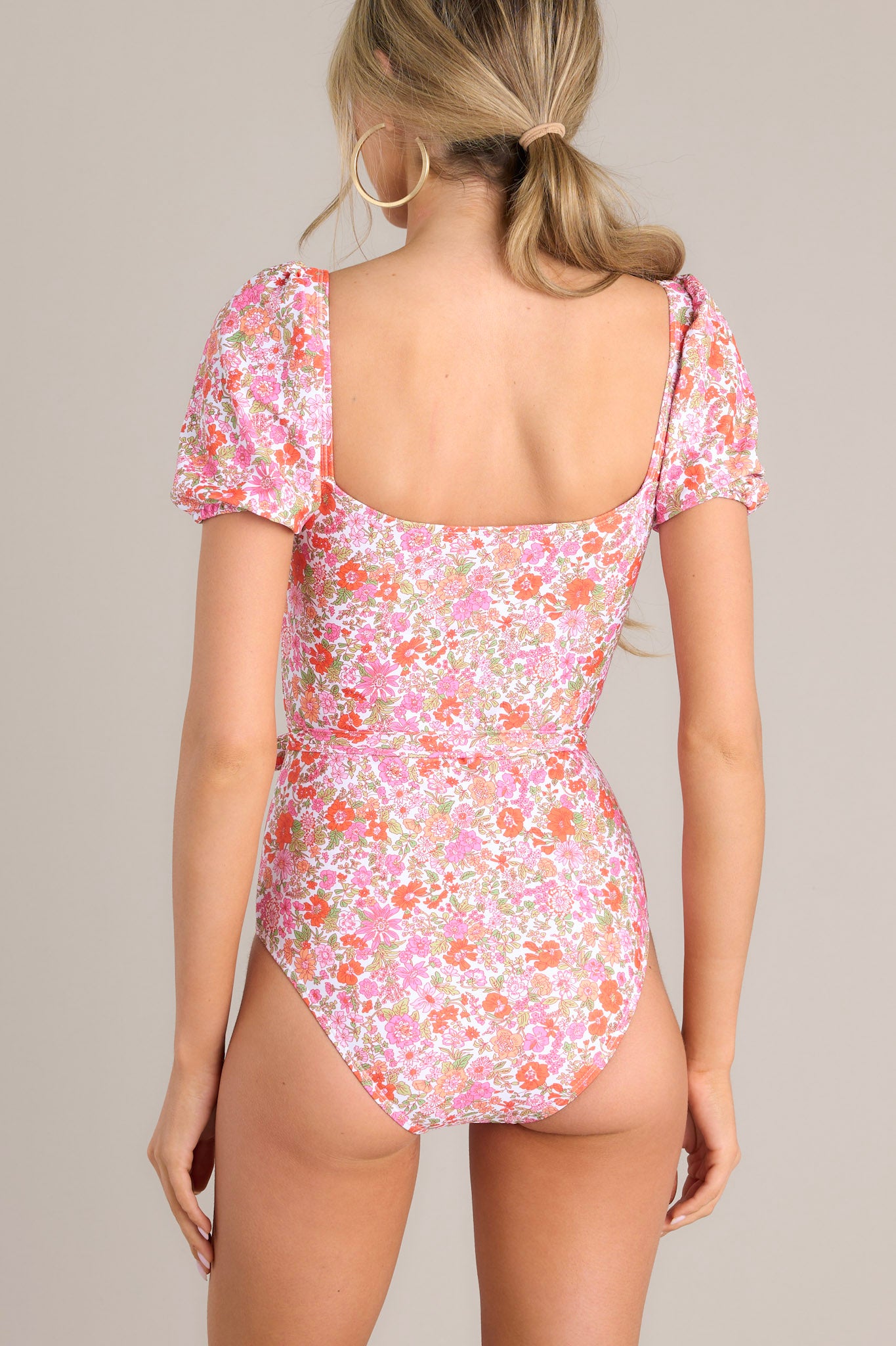 Back view of this one piece that features a square neckline, removable padding, elastic cuffed short sleeves, a removable self-tie belt, and a slightly cheeky backside. 