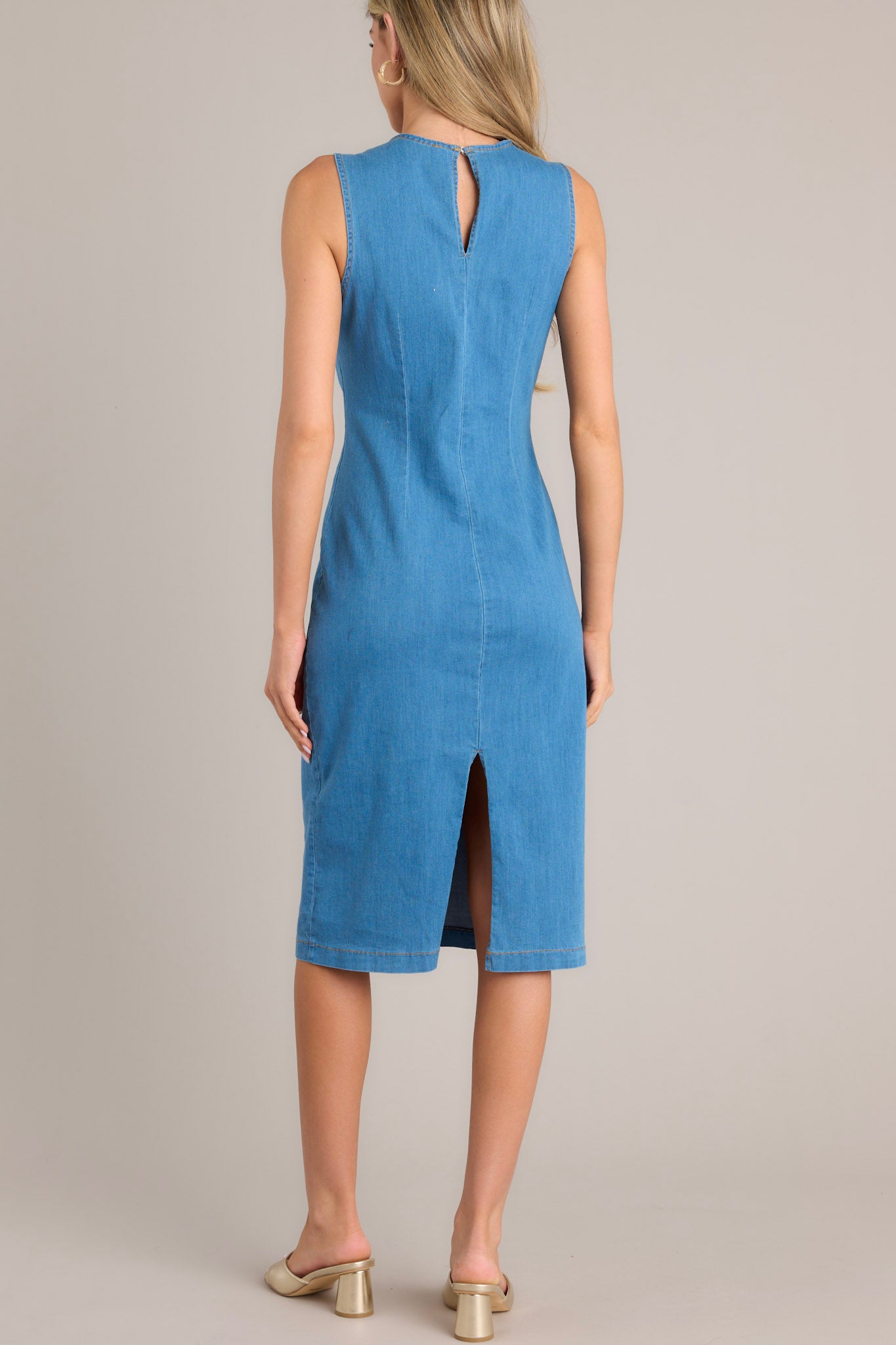 Back view of this dress that features a high crew neckline, a keyhole cutout at the back of the neck, a seam down the middle, and a slit in the back hemline.