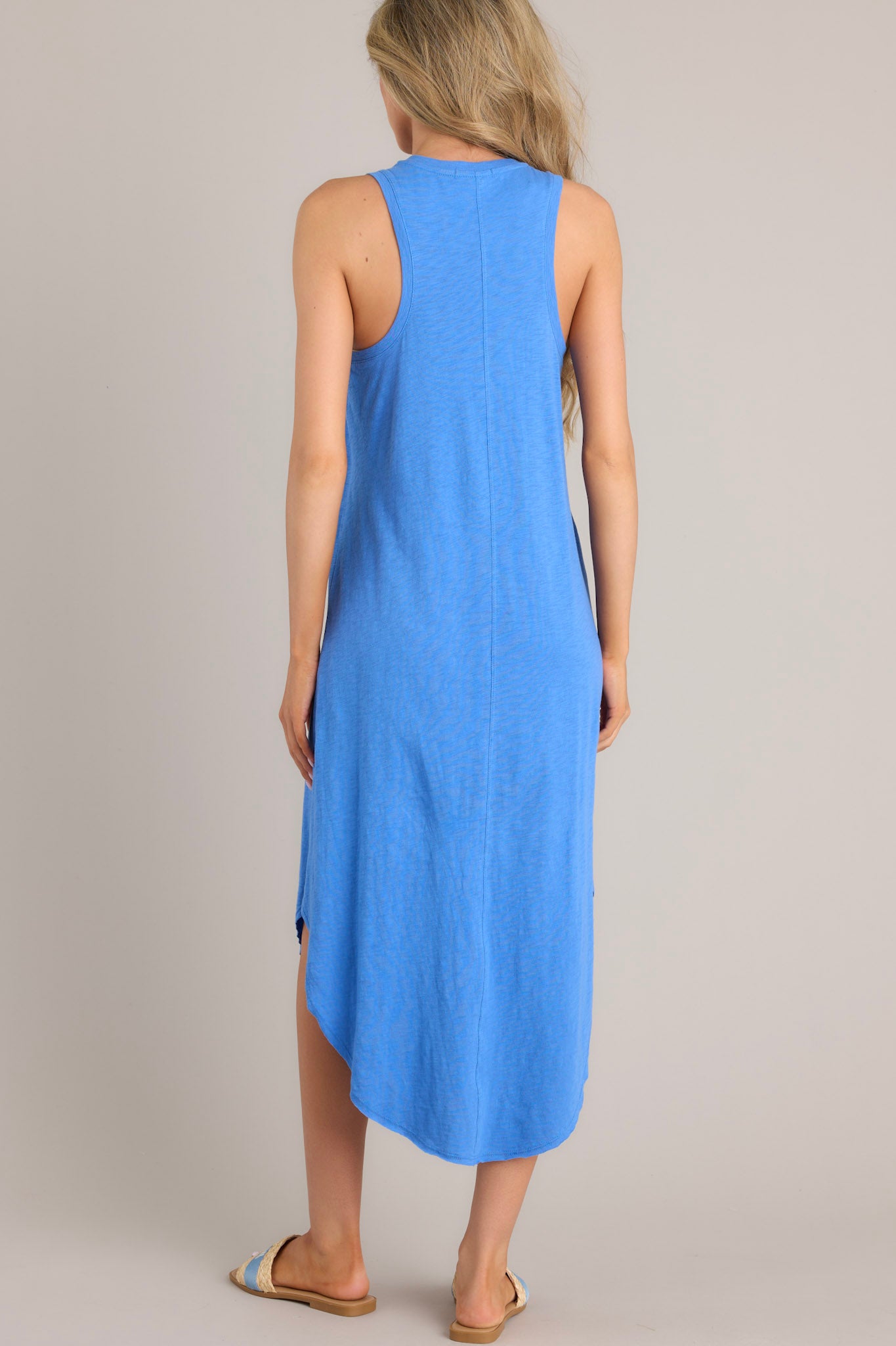 Back view of this blue midi dress that features a v-neckline, a seam down the front and back, a soft & lightweight material, and a scoop hemline.