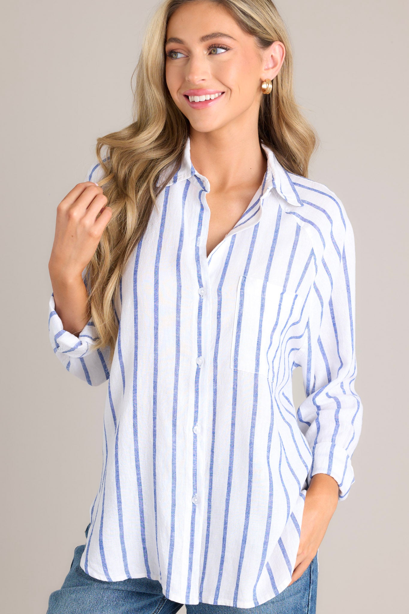 Front view of this stripe top that features a collared neckline, a functional button front, a breast pocket, button cuffed long sleeves, and a split high low hemline.