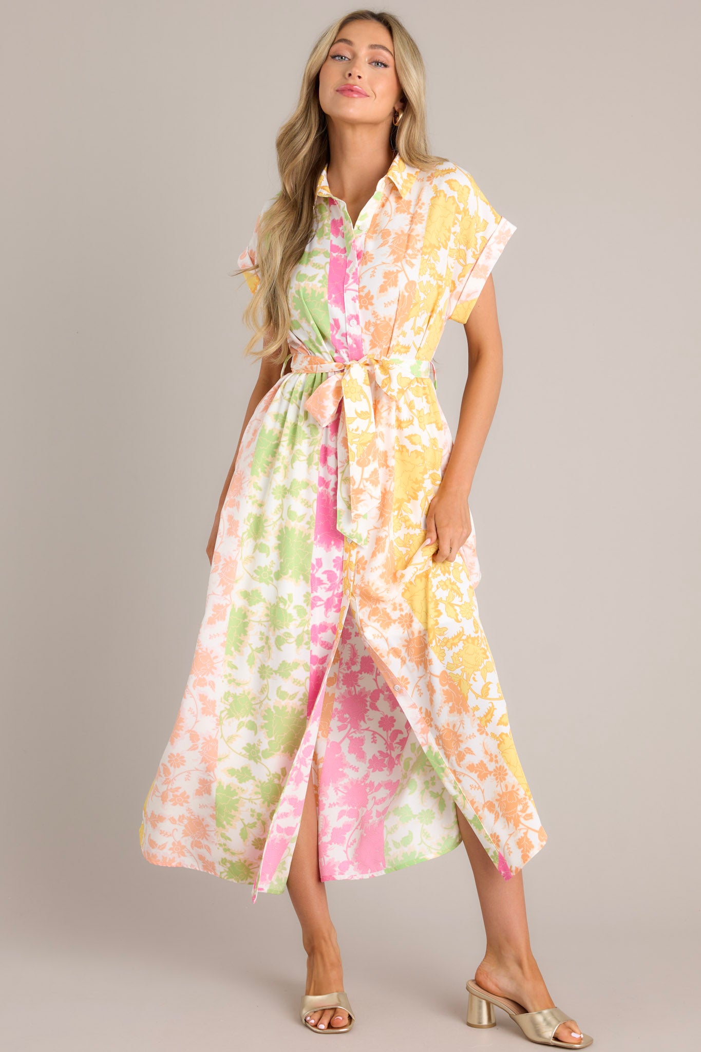 Front view of this multi floral dress that features a collared neckline, a functional button front, gathering in the waist, a self-tie waist belt, belt loops, functional hip pockets, a front slit, and wide cuffed short sleeves.