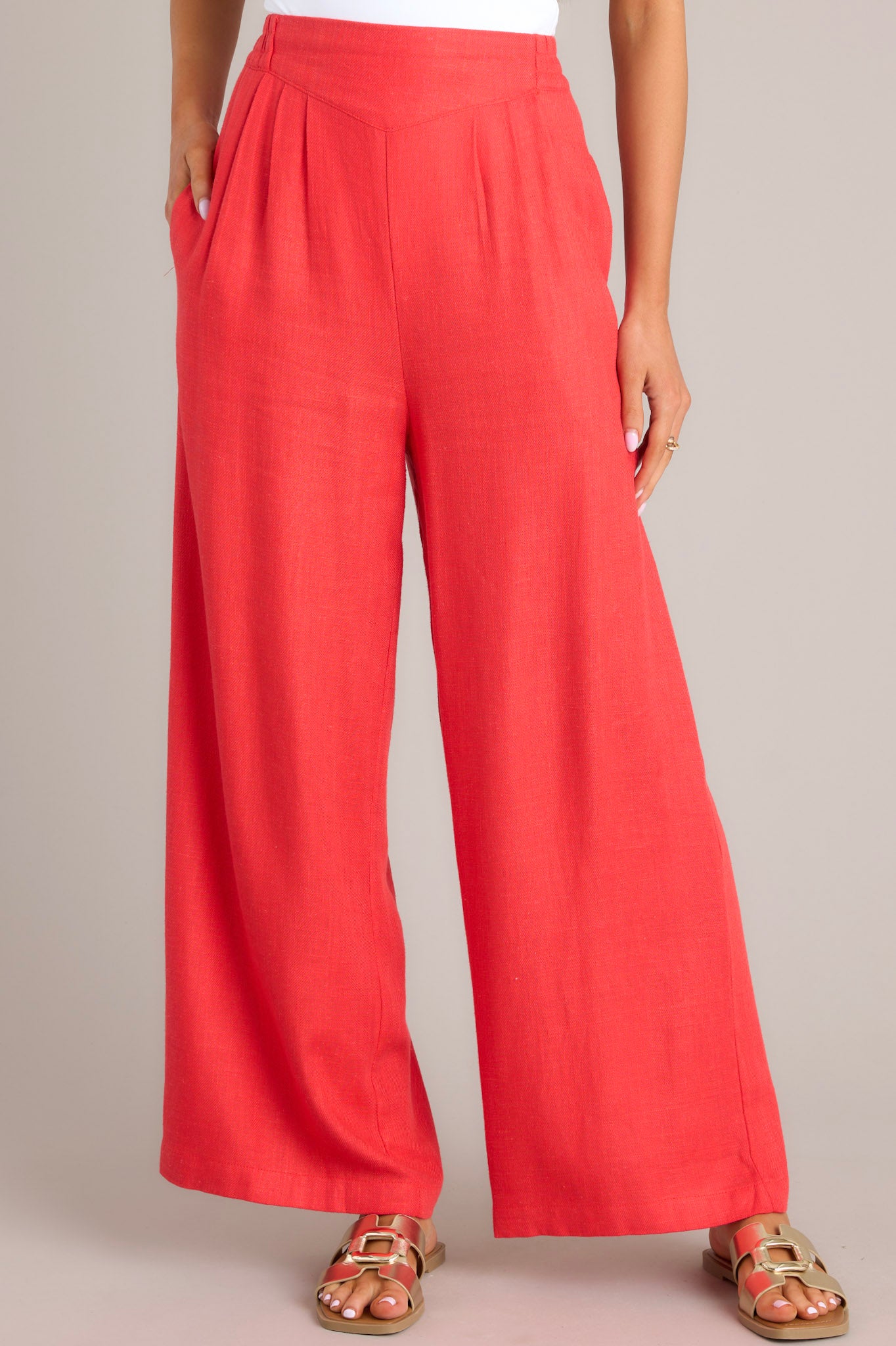 A close up view of these pants that feature a high waisted design, an elastic insert in the back, functional hip pockets, a lightweight fabric, and a wide leg design.