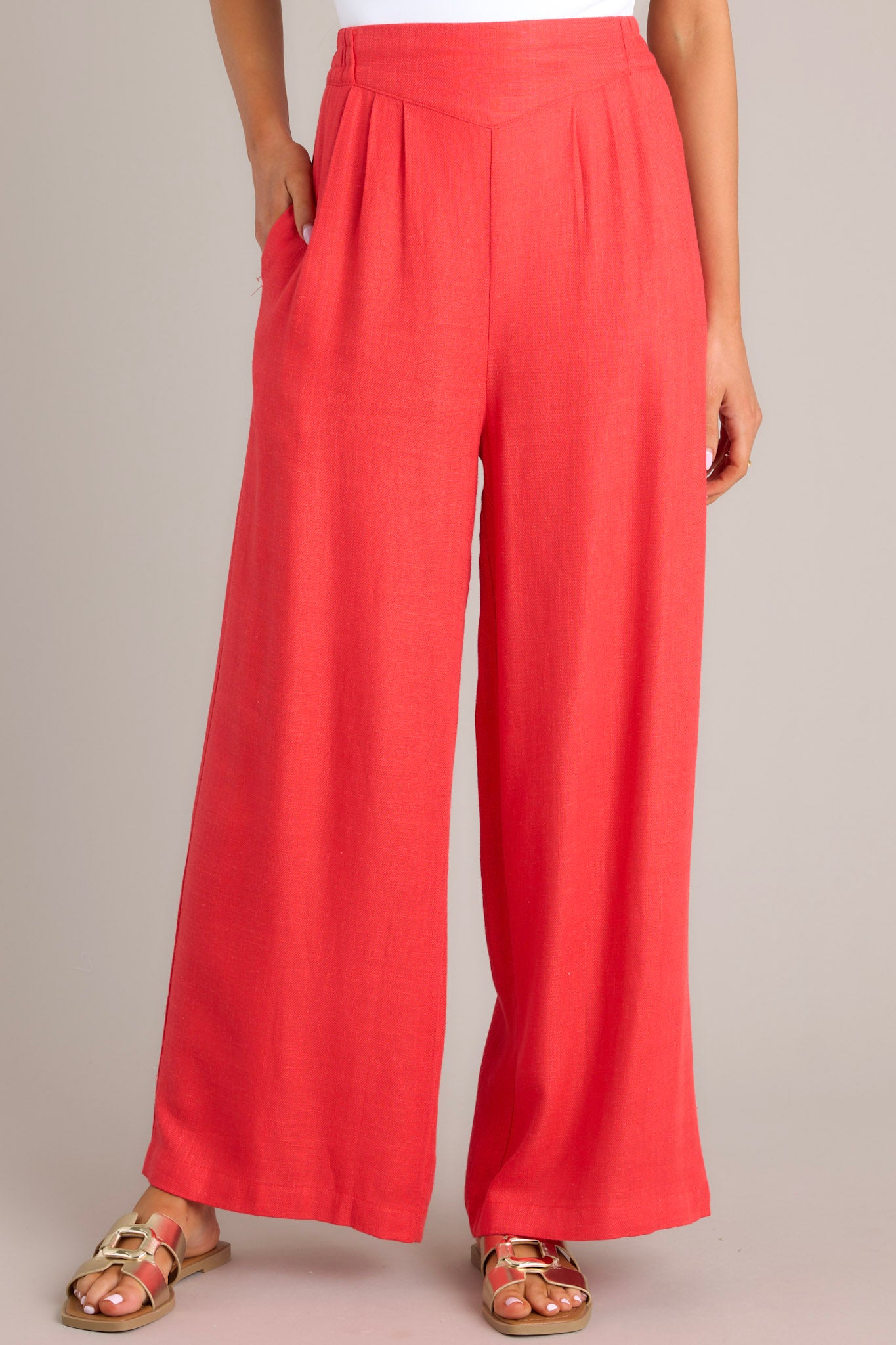 An angled close up of these pants that feature a high waisted design, an elastic insert in the back, functional hip pockets, a lightweight fabric, and a wide leg design.