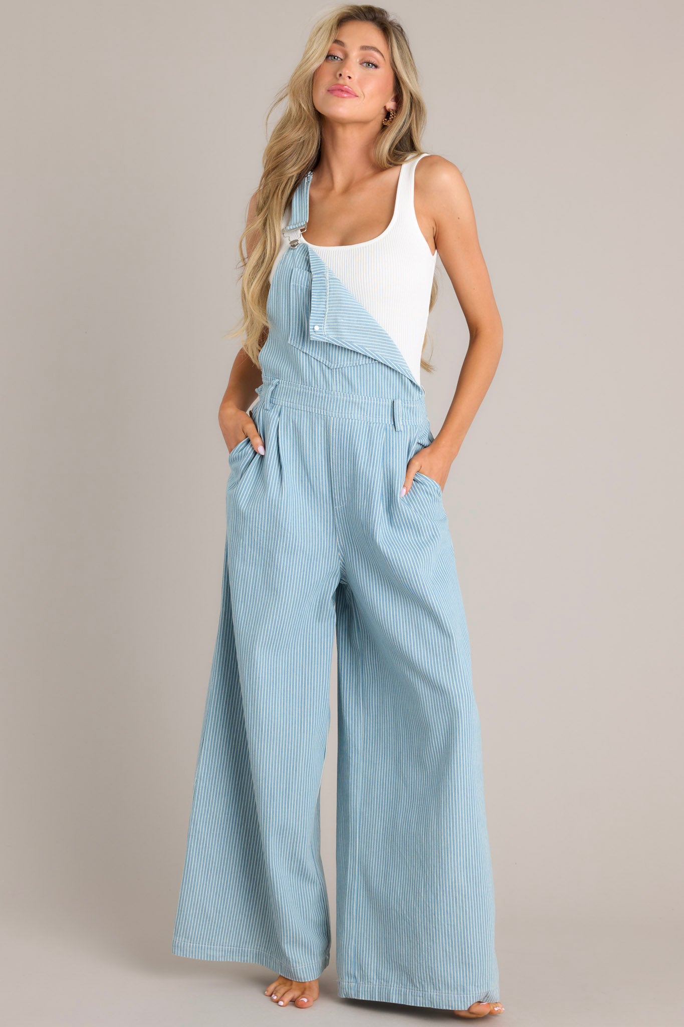 Full view of these overalls that feature a square neckline, adjustable shoulder straps that buckle in the front, a functional center bust pocket, belt loops, functional hip buttons, functional front & back pockets, and a wide leg.