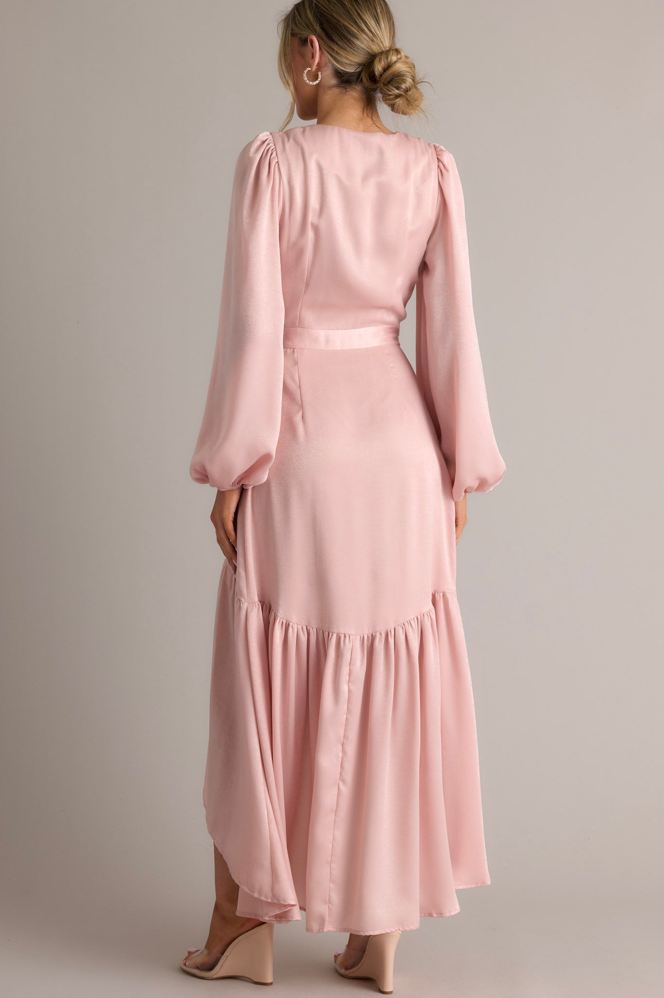 Back view of this wrap dress that features a v-neckline, balloon sleeves, an adjustable tie around the waist, and an asymmetrical flowy skirt.