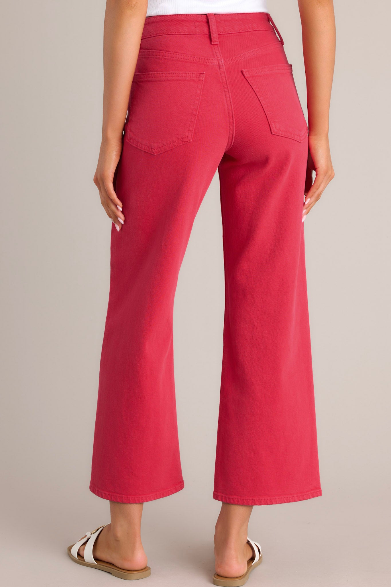 Back view of these red jeans that feature a high waisted design, classic button & zipper closure, belt loops, functional front & back pockets, and a cropped length.