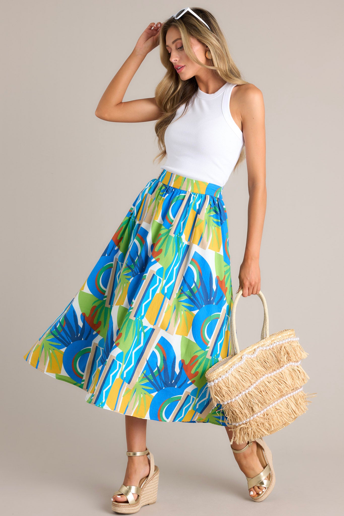 This blue midi skirt features a high waisted design, a thick waistband, a discrete side zipper, functional hip pockets, and a flowing silhouette.