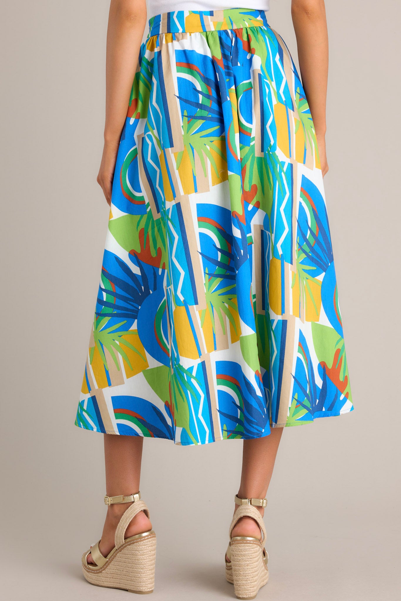 Back view of a colorful, high-waisted A-line skirt with abstract patterns in blue, green, and yellow.