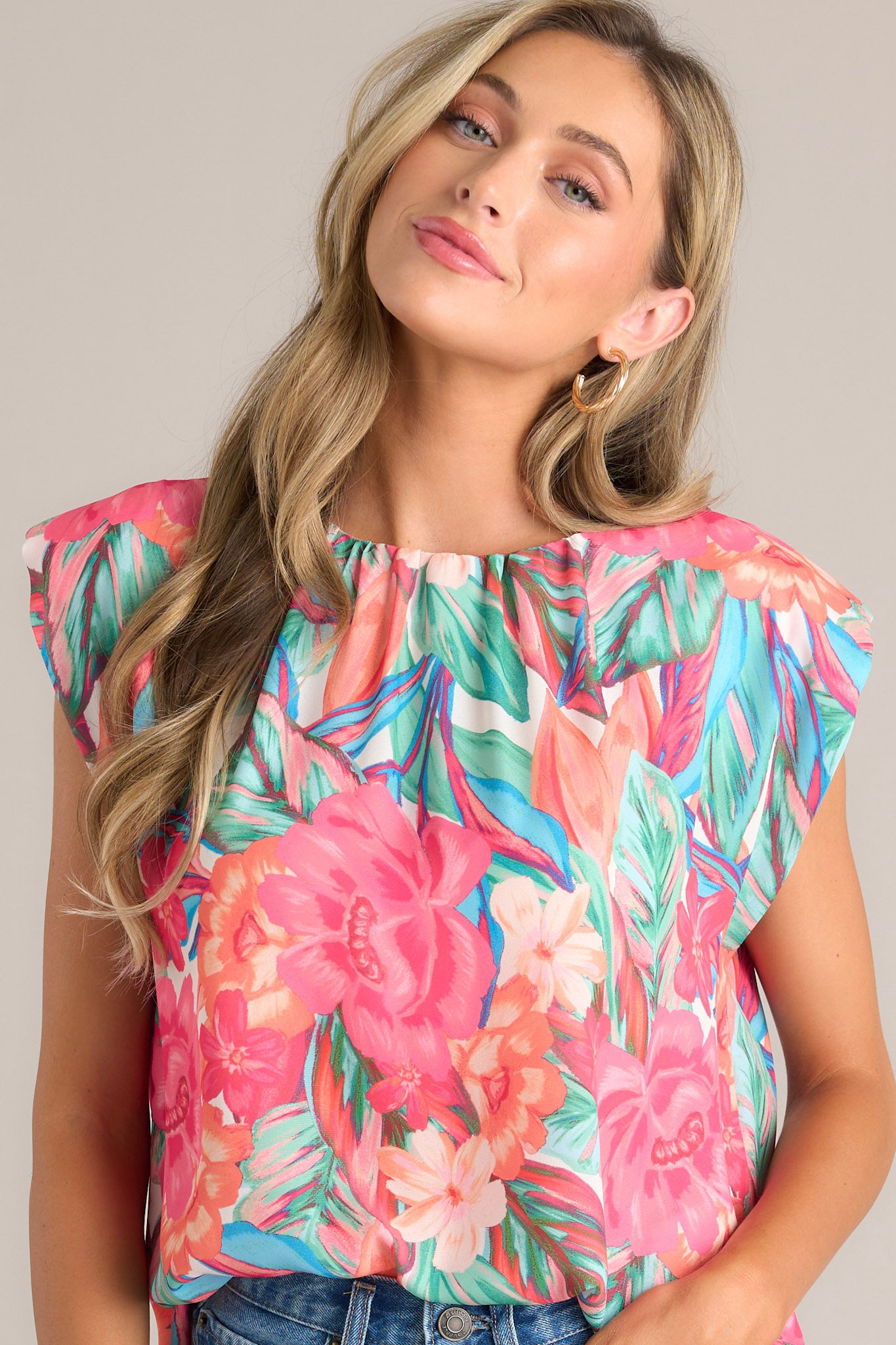 Angled front view of this hot pink floral top that features a crew neckline, shoulder padding, wide short sleeves, and a tropical floral print.