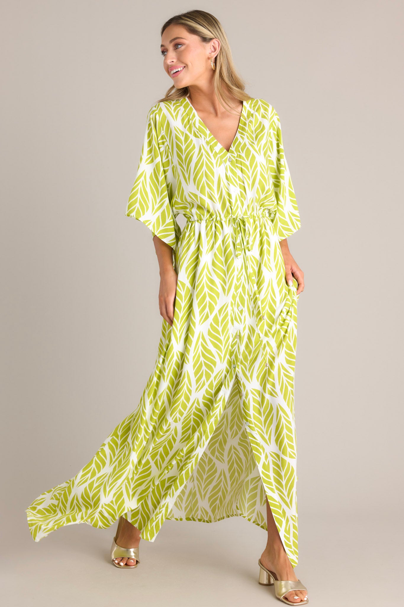 Side view of this lime green maxi dress that features a v-neckline, a functional button front, a self-tie drawstring waist, a flowing silhouette, and flowing half sleeves.