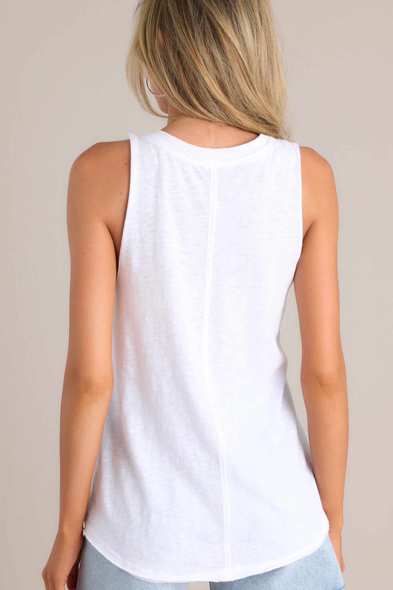 Back view of this white tank that features a v-neckline, a sleeveless design, a classic color, and a scoop hemline.