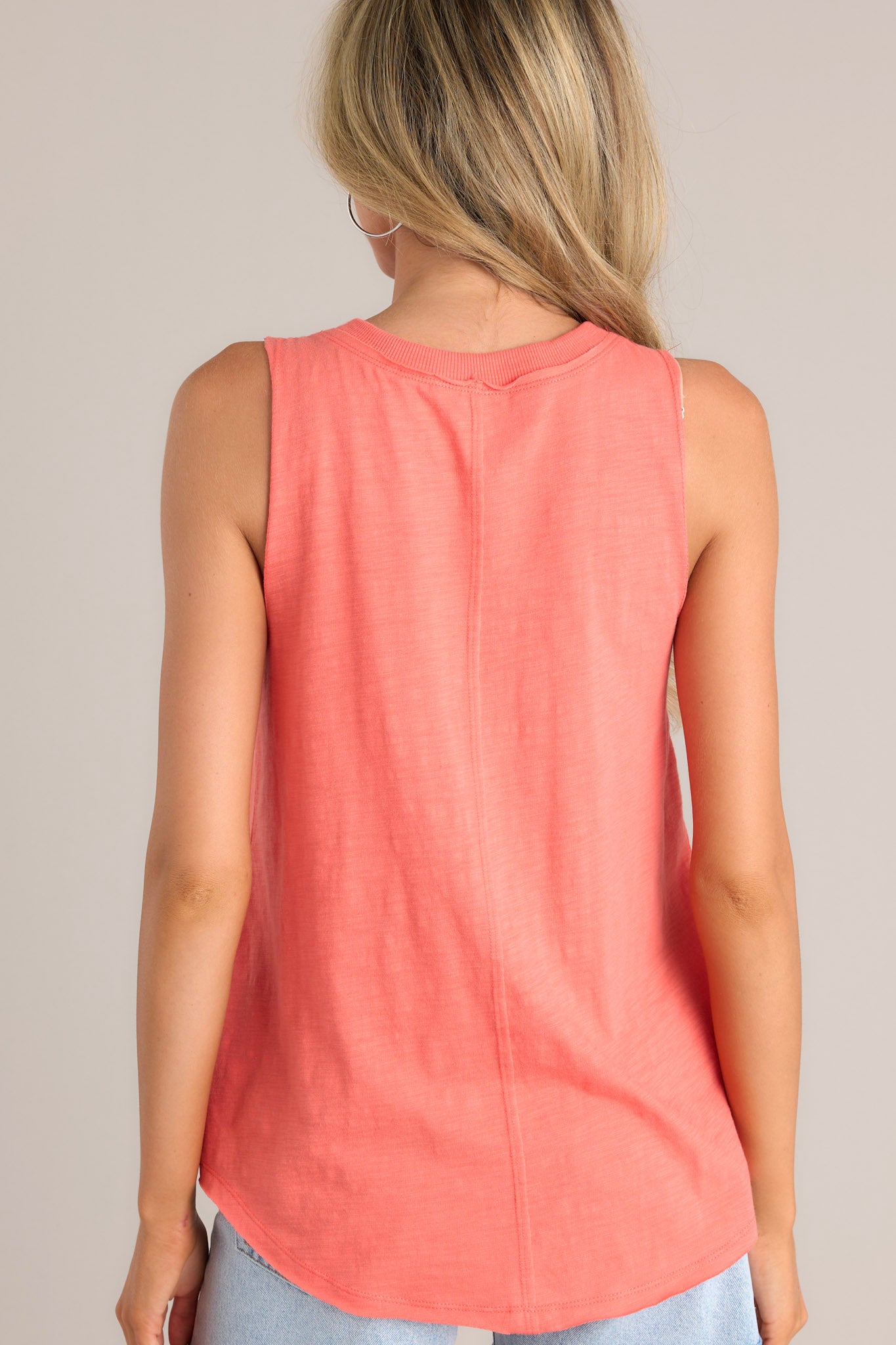 Back view of this tank that features a v-neckline, a sleeveless design, a bold color, and a scoop hemline.