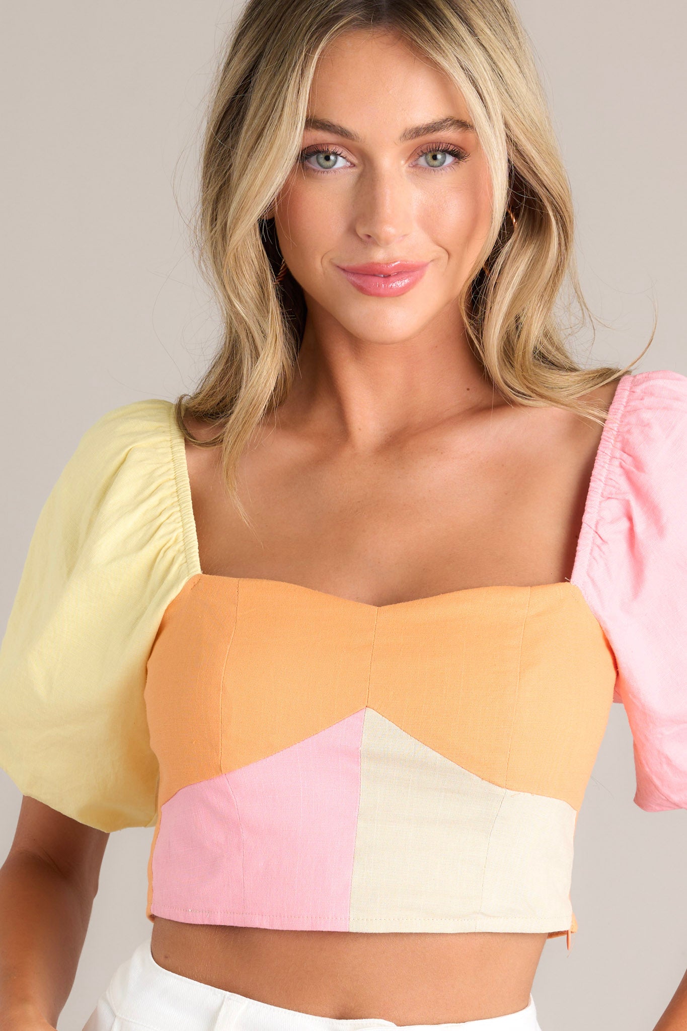 This pastel crop top features a sweetheart neckline, a self-tie back feature, a fully smocked back, a discrete side zipper, and elastic cuffed short puff sleeves.