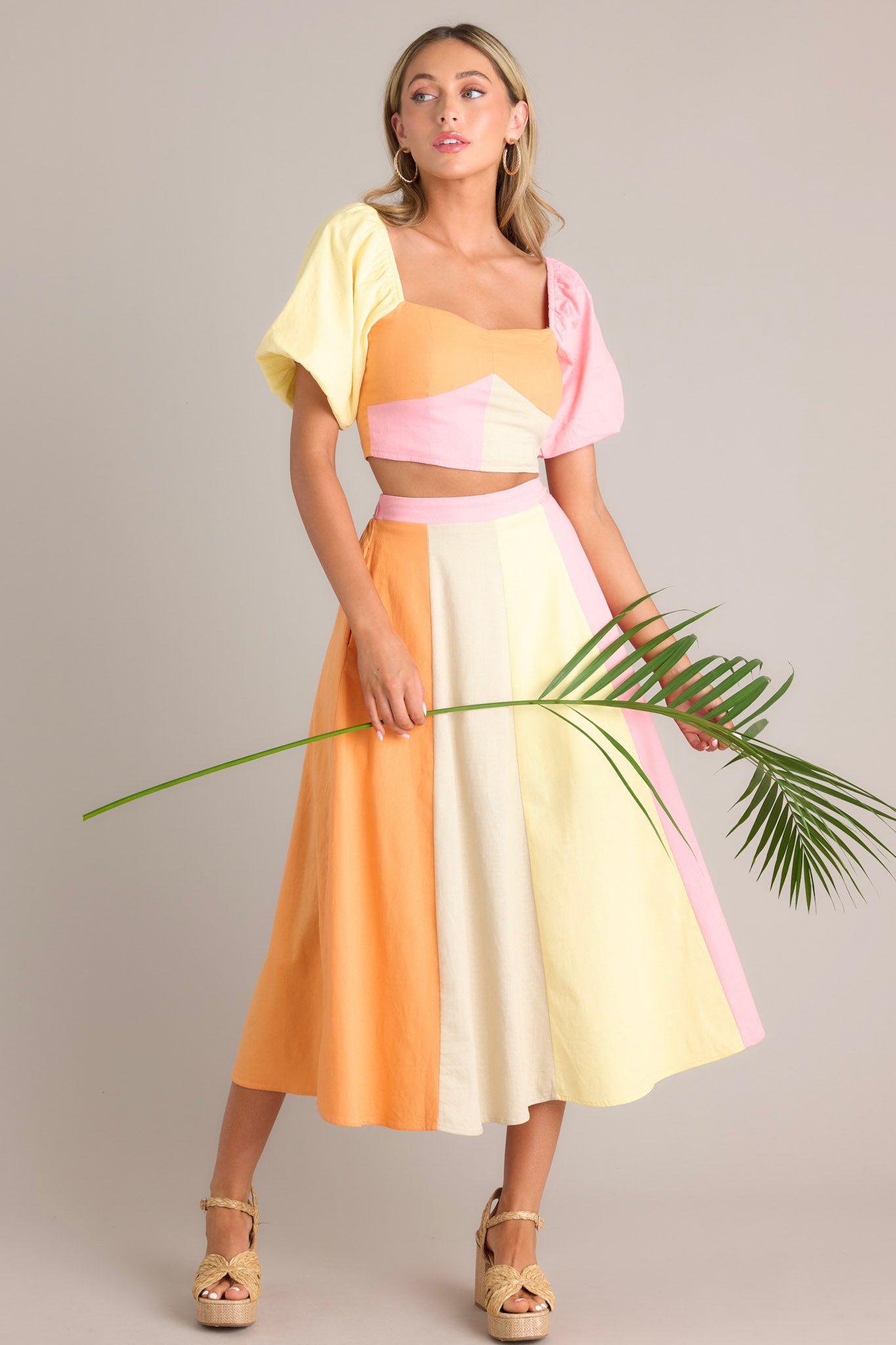 This pastel midi skirt features a high waisted design, an elastic insert in the back of the waist, a discrete side zipper, functional hip pockets, and a flowing silhouette.