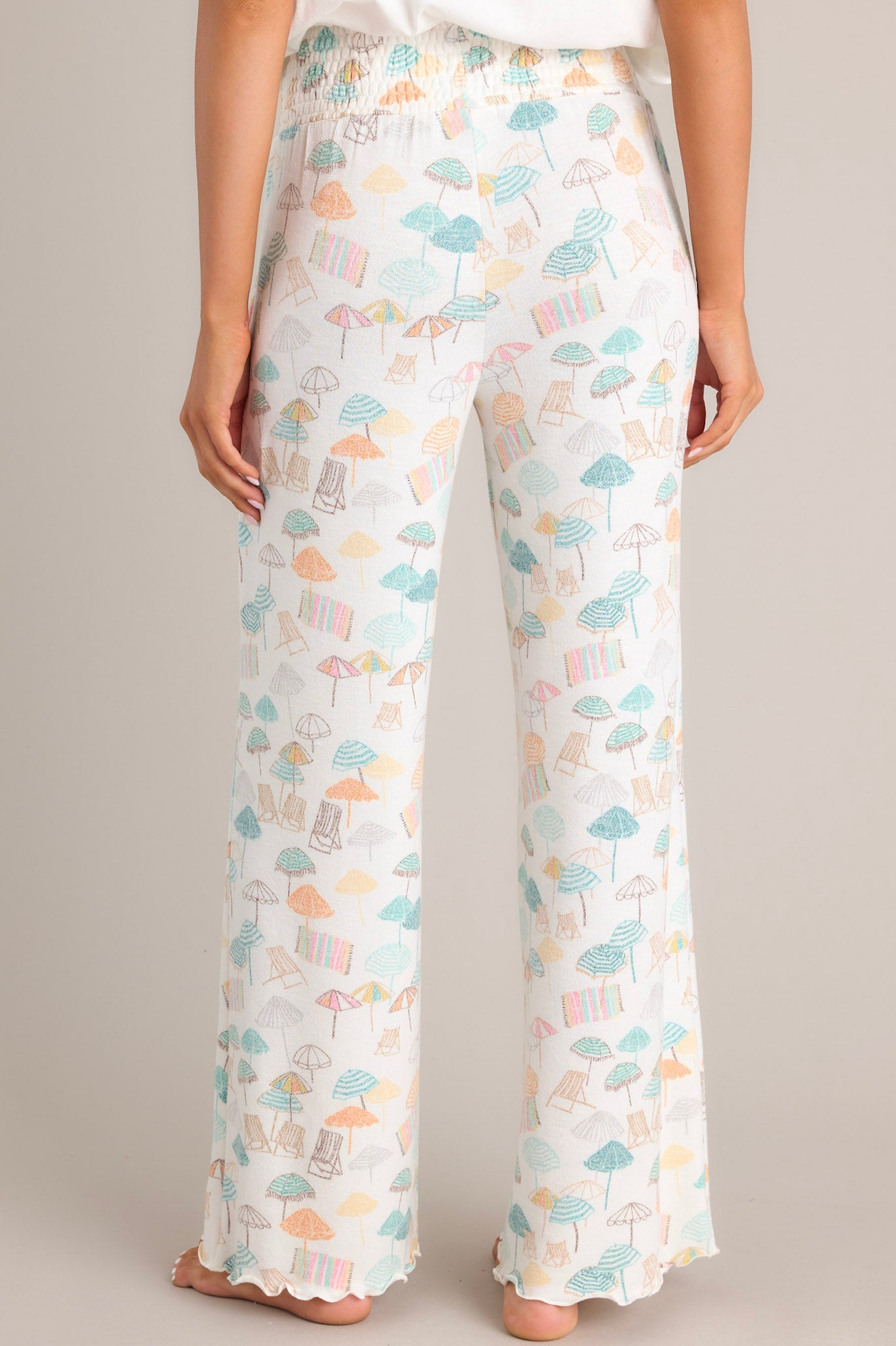 Back view of these pants that feature a high-waisted design, fully smocked waistband, super soft material, wide leg, and a scalloped hemline.